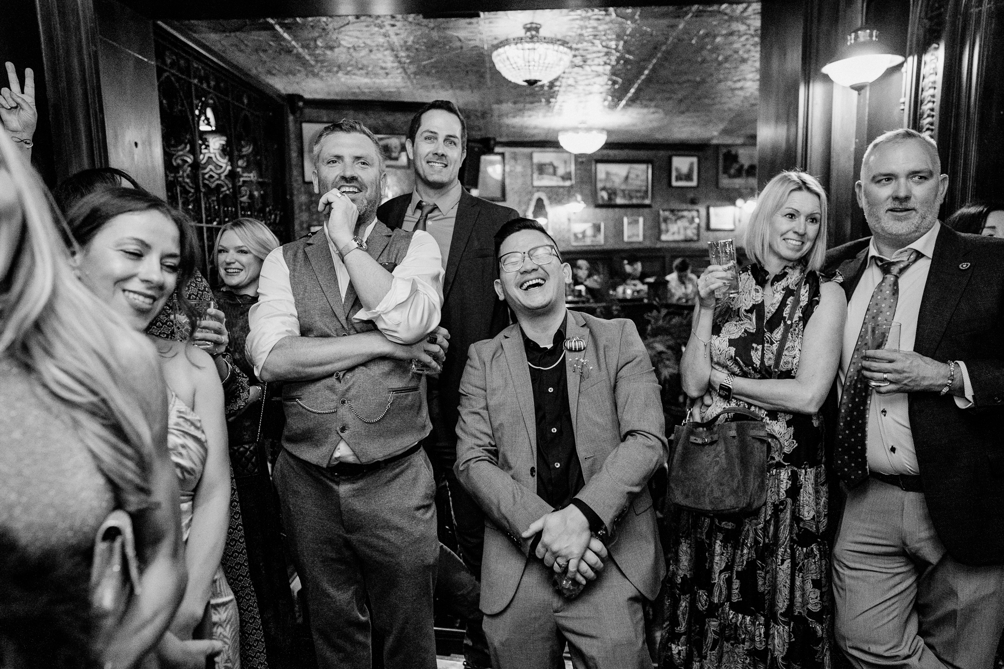 Black and white group portrait of smiling wedding guests during a reception at J.R. Mahon's Dublin