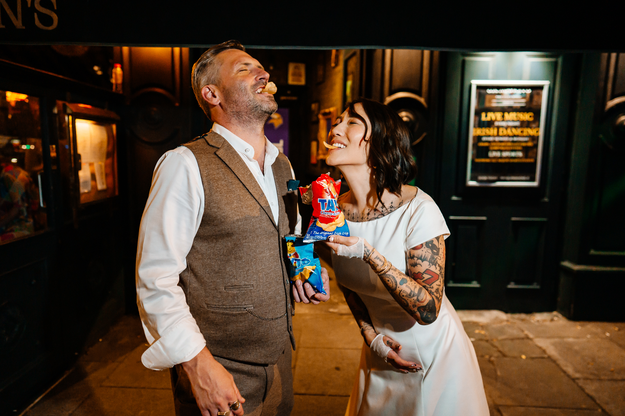 Bride and groom sharing a playful moment with Tayto crisps during their wedding evening at J.R. Mahon's Dublin