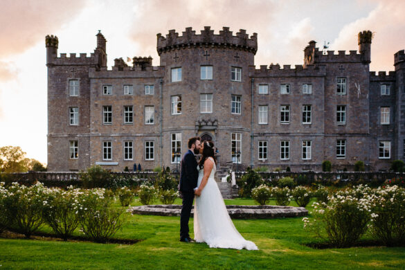 Bride and groom posing in the gardens with Markree Castle in the background on their wedding day in Sligo, Ireland