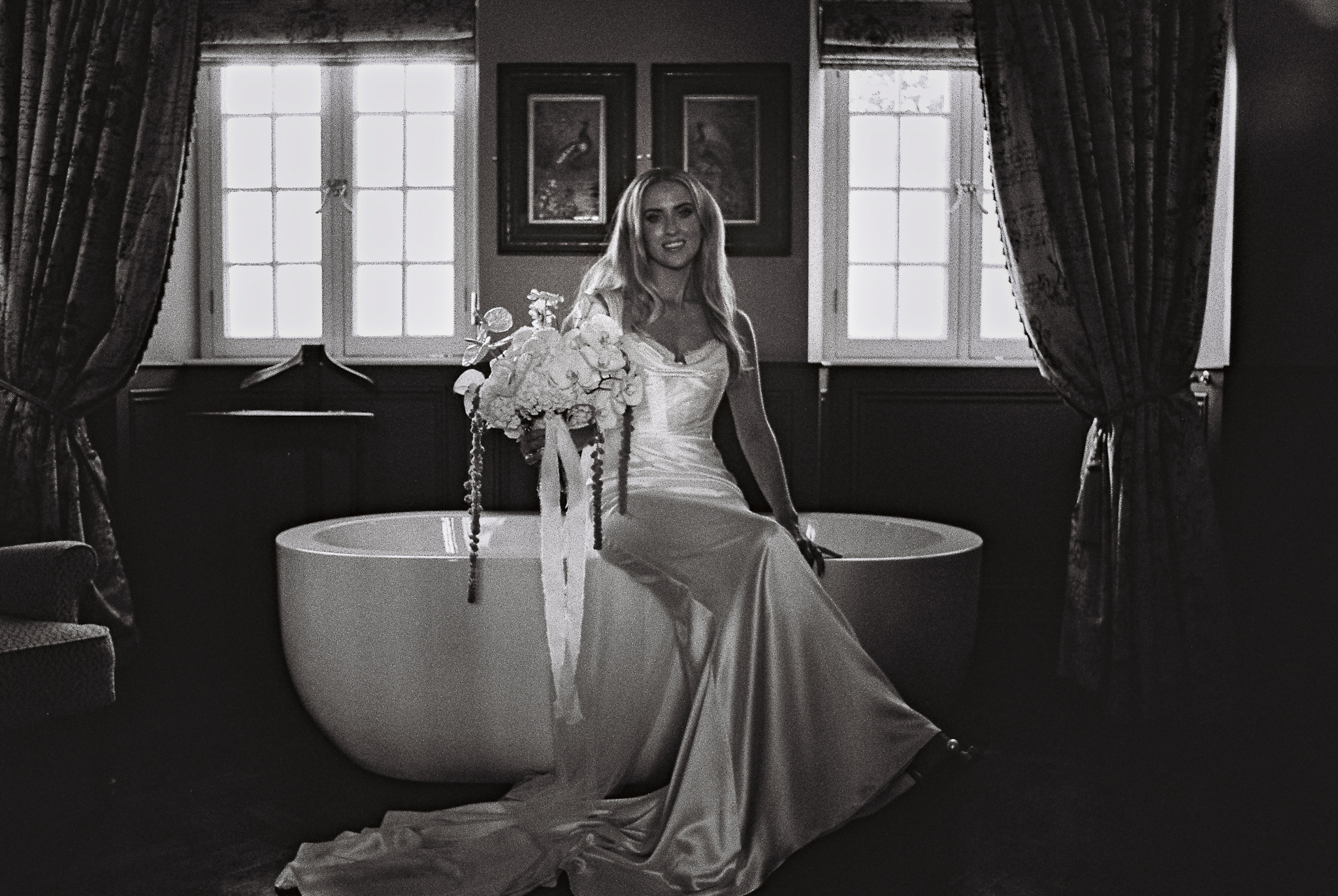 Black and white 35mm film wedding portrait of a bride beside a freestanding bathtub in a historic room at Markree Castle, County Sligo, Ireland.
