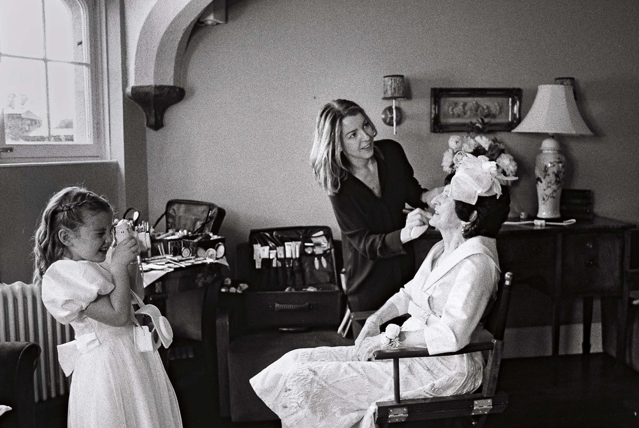 Black and white 35mm film photograph of a bride having her makeup finished during wedding morning preparations at Markree Castle in Sligo, Ireland.