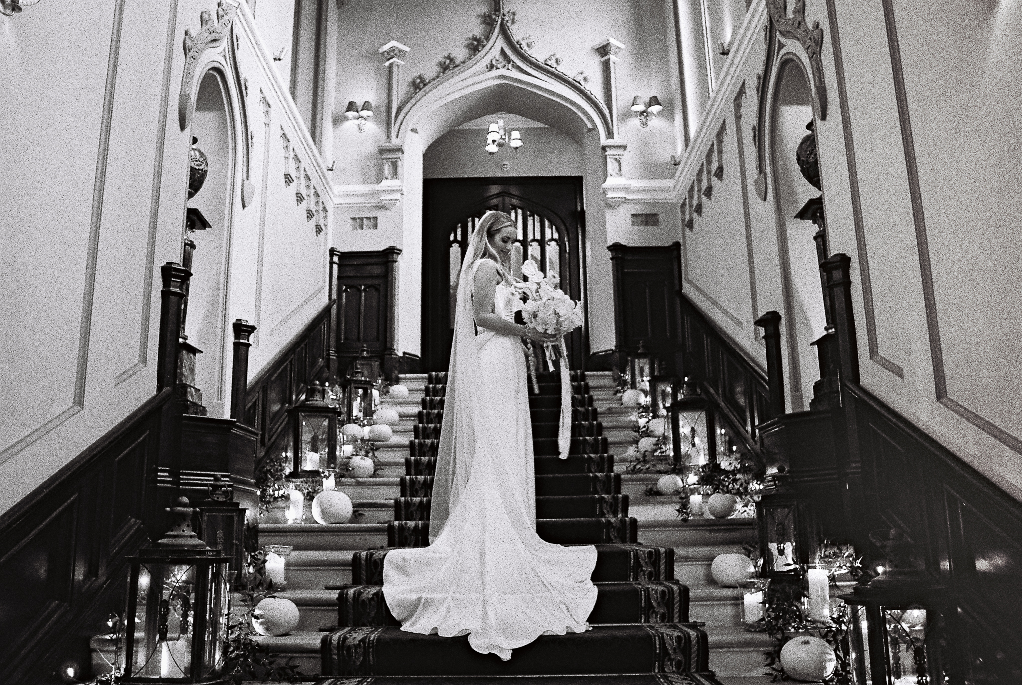 Black and white 35mm film photograph of a bride standing on the grand staircase at Markree Castle in Sligo, Ireland.