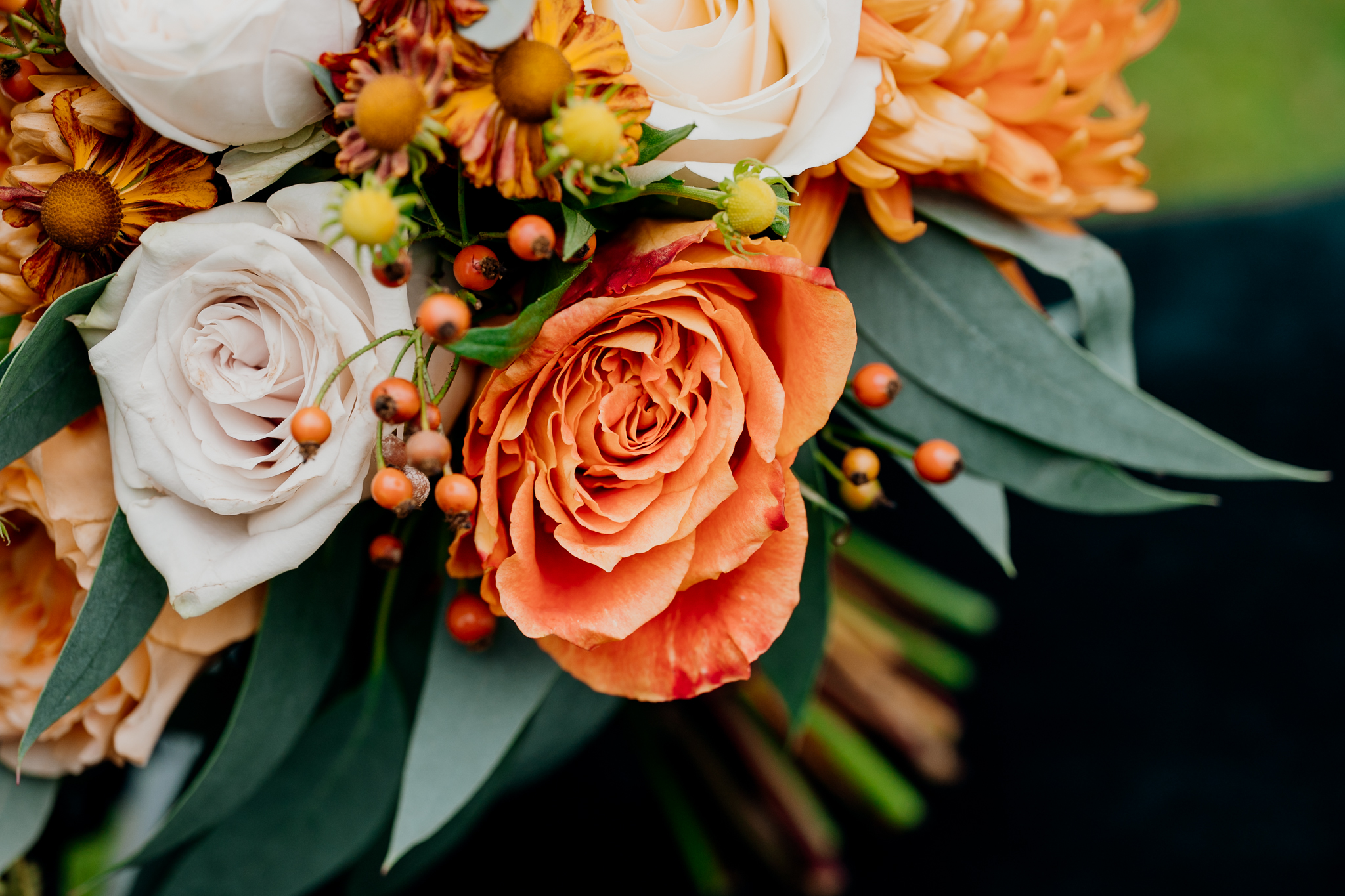 Close-up of a peach-orange rose surrounded by colourful autumn wedding flowers in a bridal bouquet by The Flower Shed.