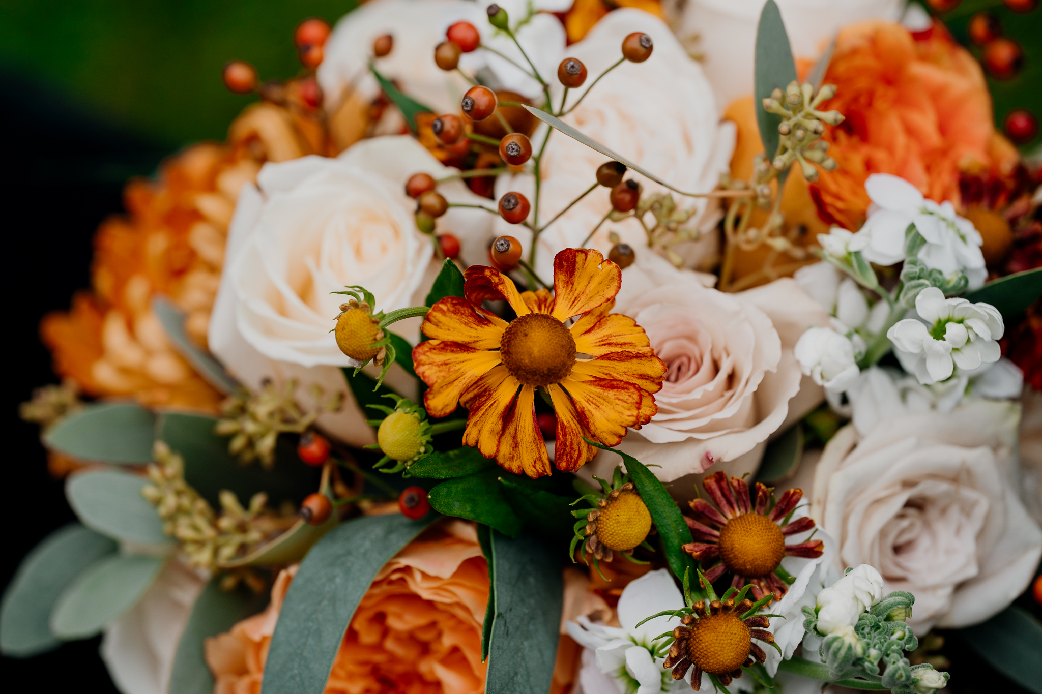 Close-up of white roses, yellow sunflowers and orange seasonal flowers in a Markree Castle wedding bouquet.