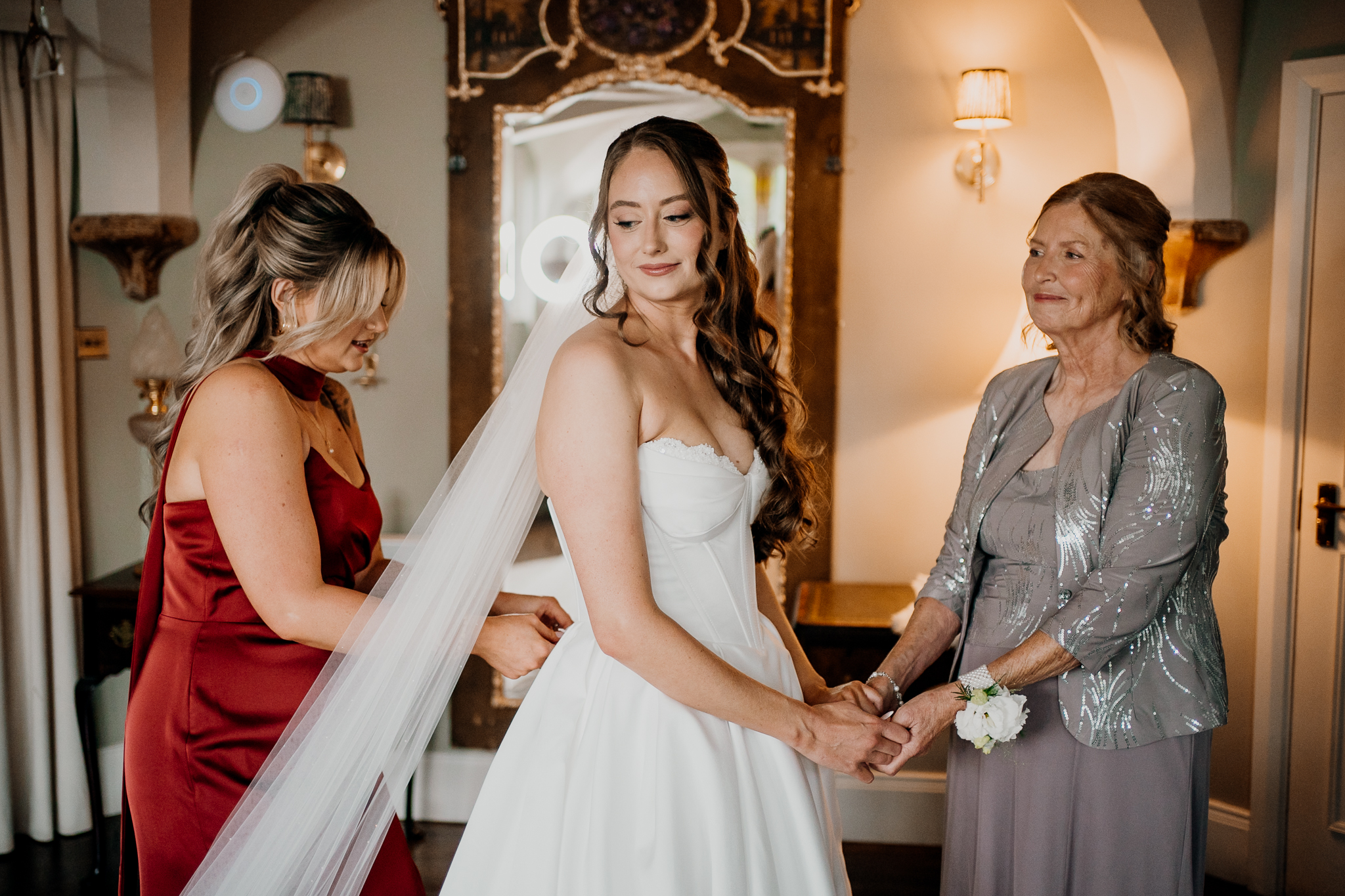 Bride smiling over her shoulder while bridesmaids help with her wedding dress at Markree Castle.