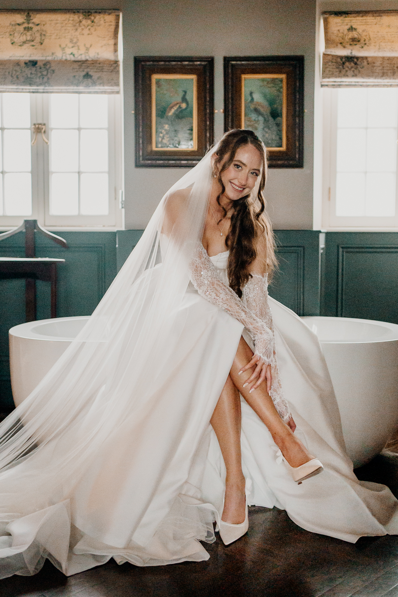 Bride in a white wedding gown sitting beside a window at Markree Castle with soft natural light illuminating her dress.