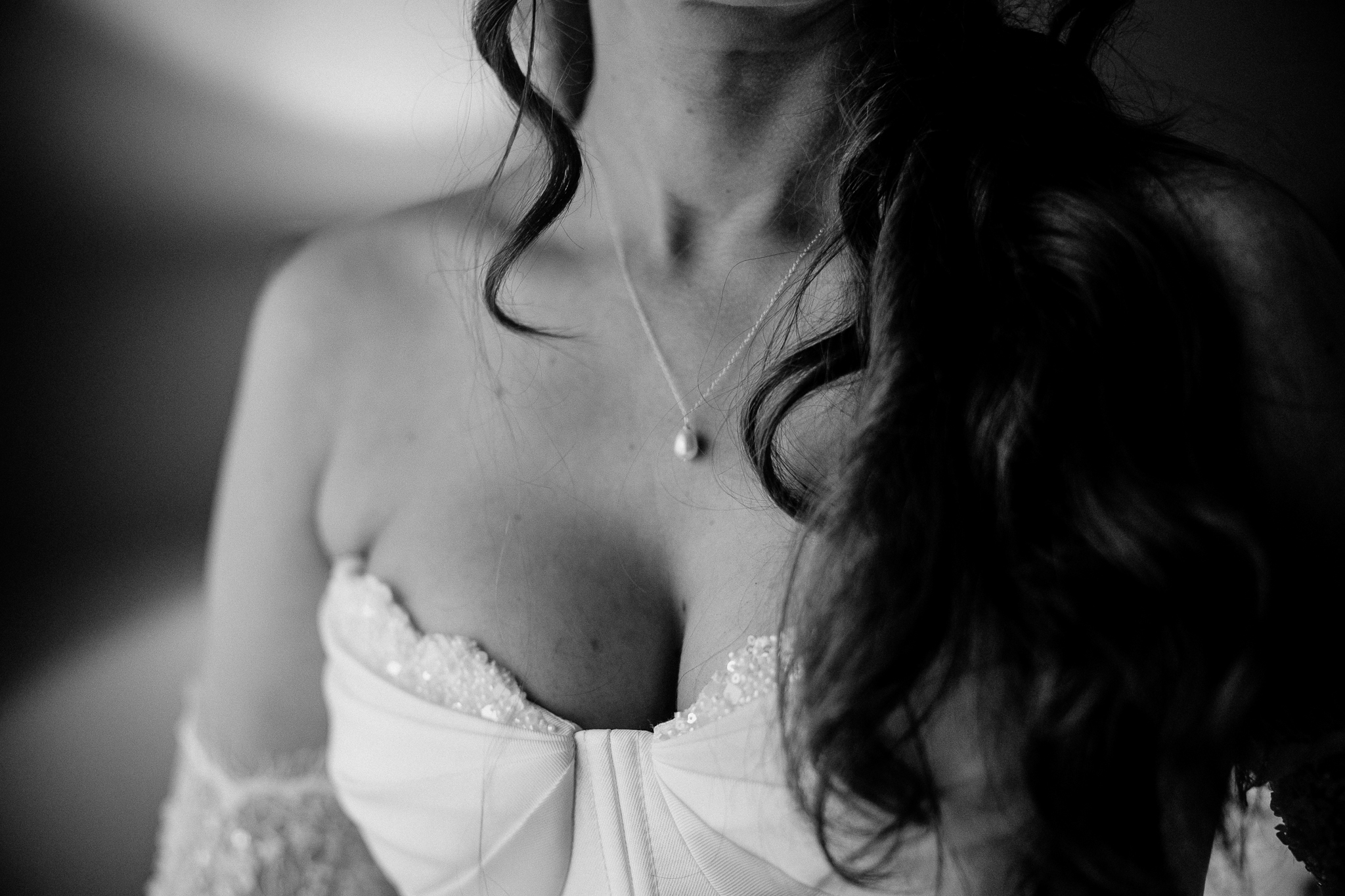 Black and white close-up of a bride's necklace and curled hair during wedding preparations at Markree Castle.
