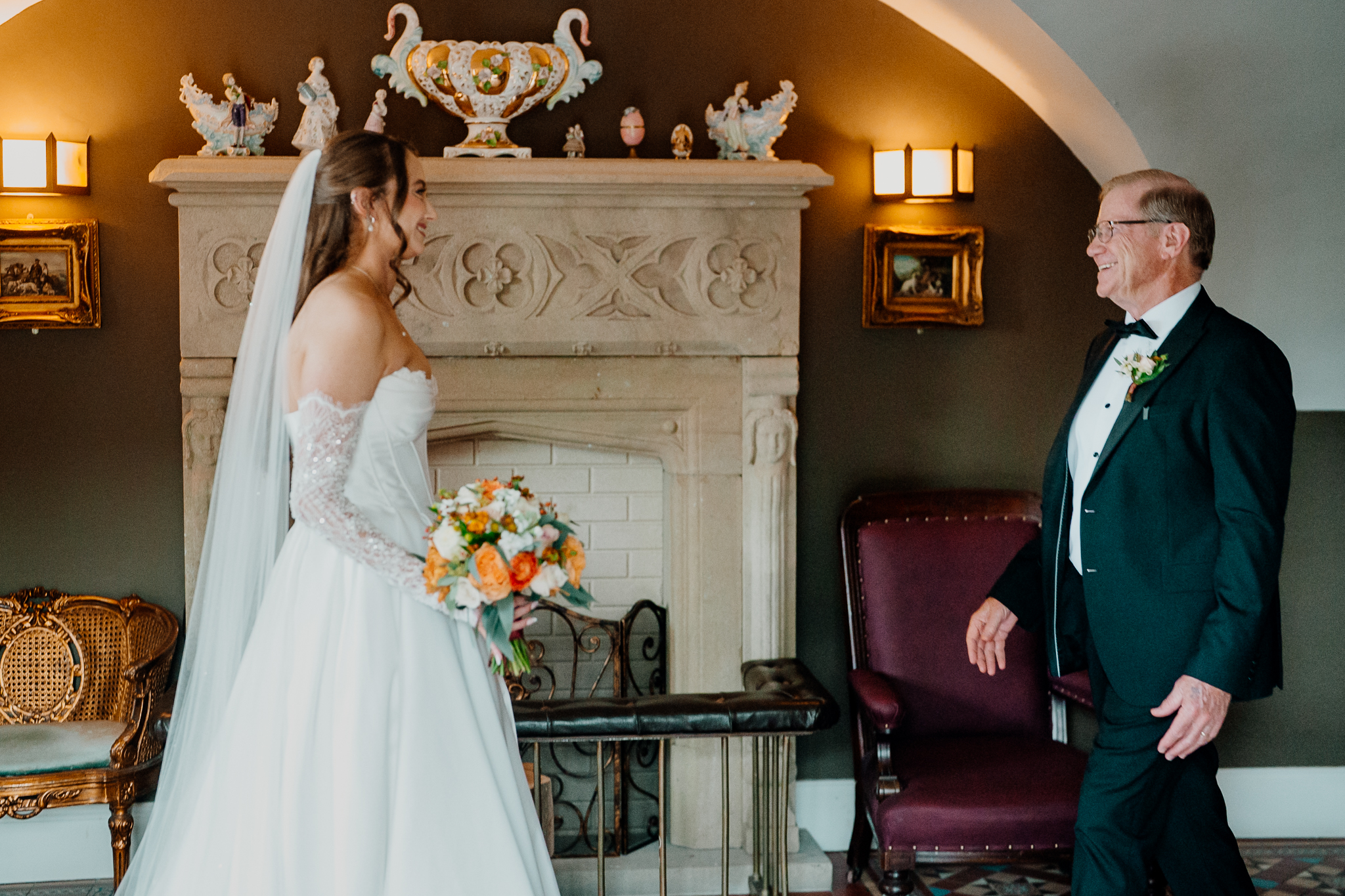 Bride in a white wedding dress standing beside an ornate stone fireplace inside Markree Castle.
