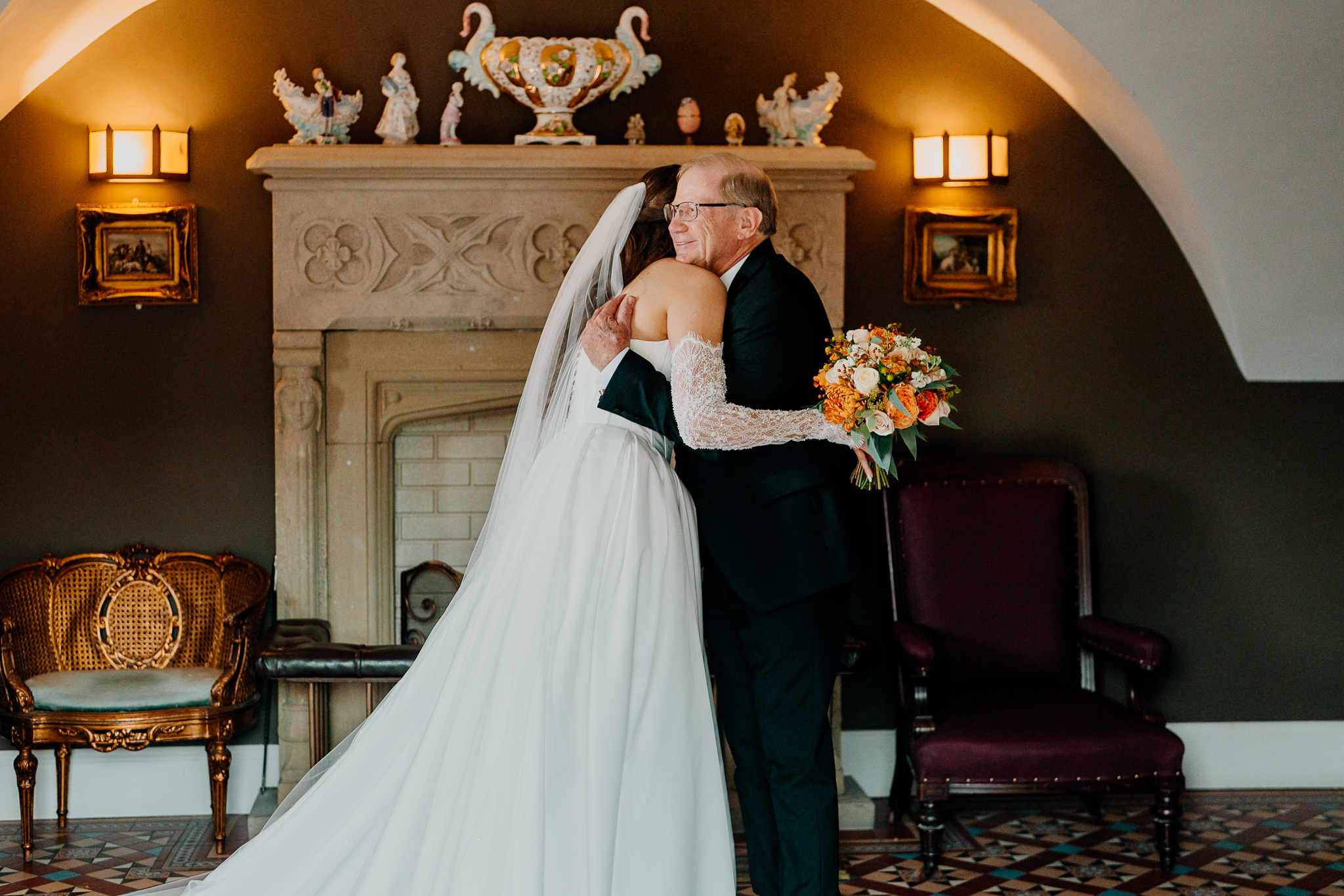 Bride sharing a warm embrace with a family member beside the ornate fireplace at Markree Castle.