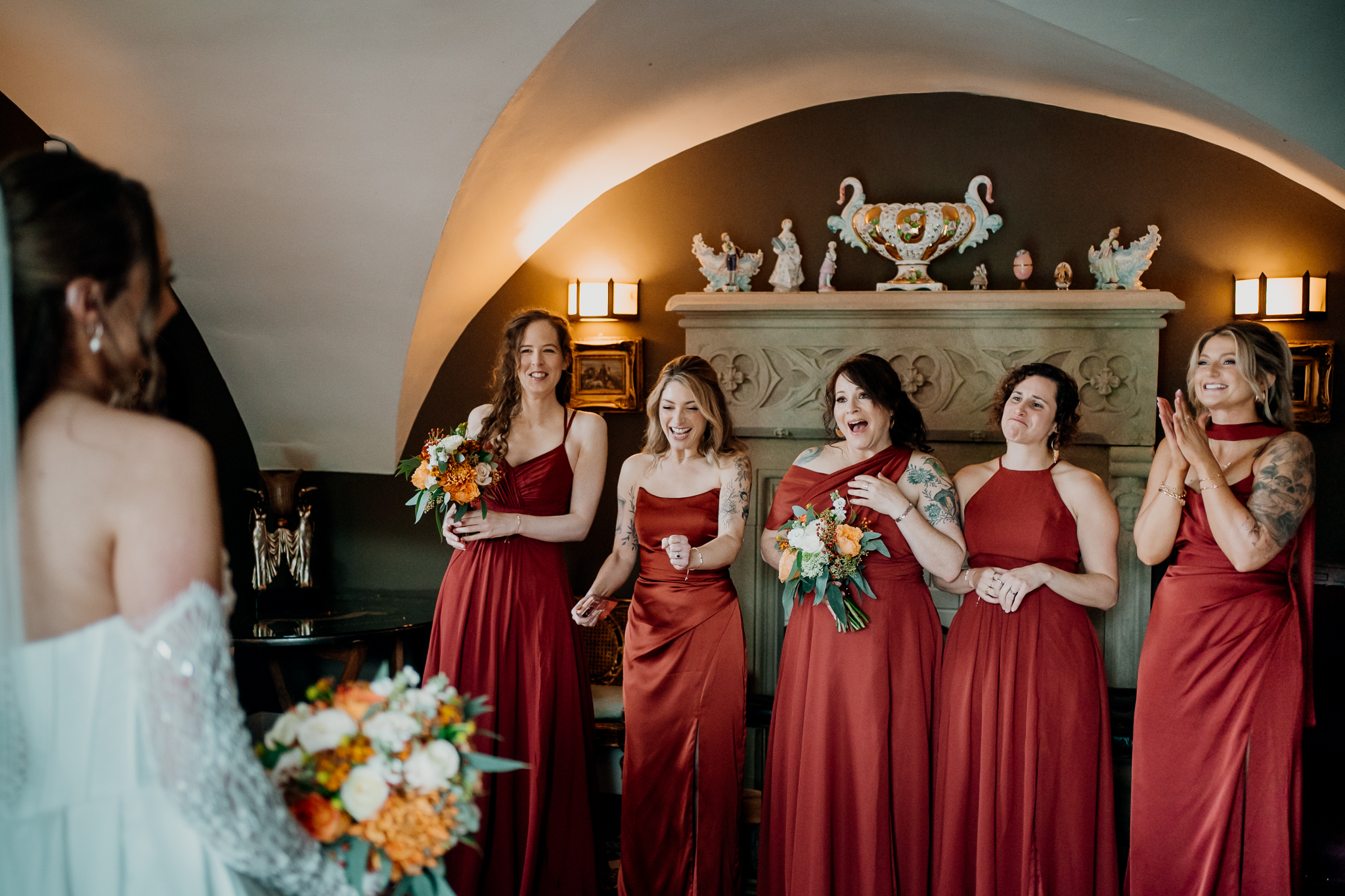 Bride and bridesmaids in burgundy dresses posing together beneath an arched ceiling inside Markree Castle.