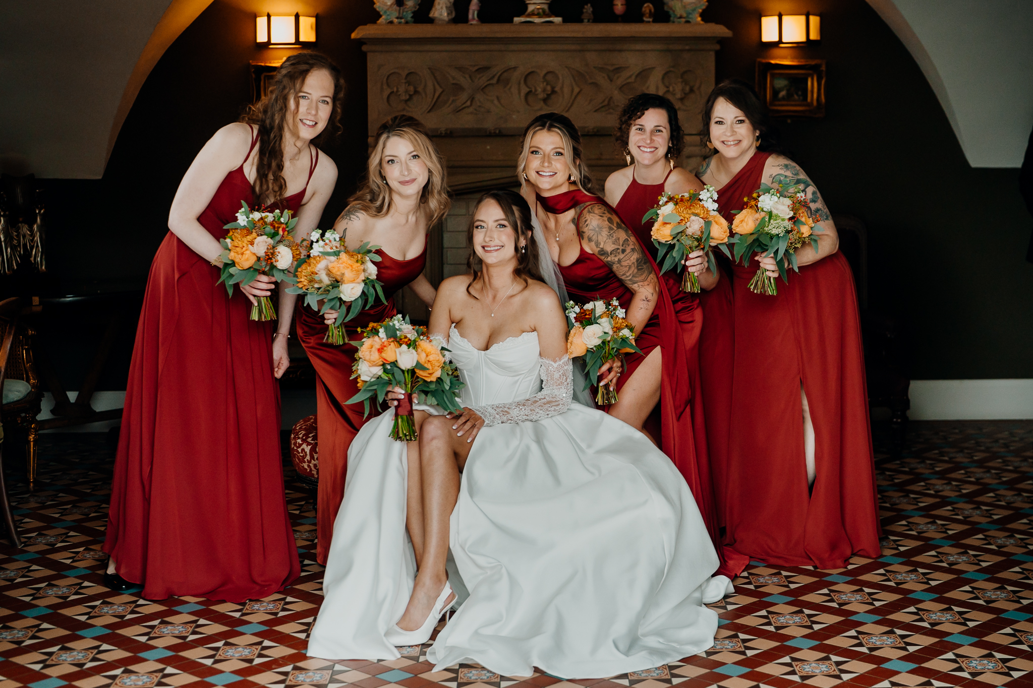 Bride with bridesmaids wearing burgundy dresses and holding colourful autumn bouquets inside Markree Castle.