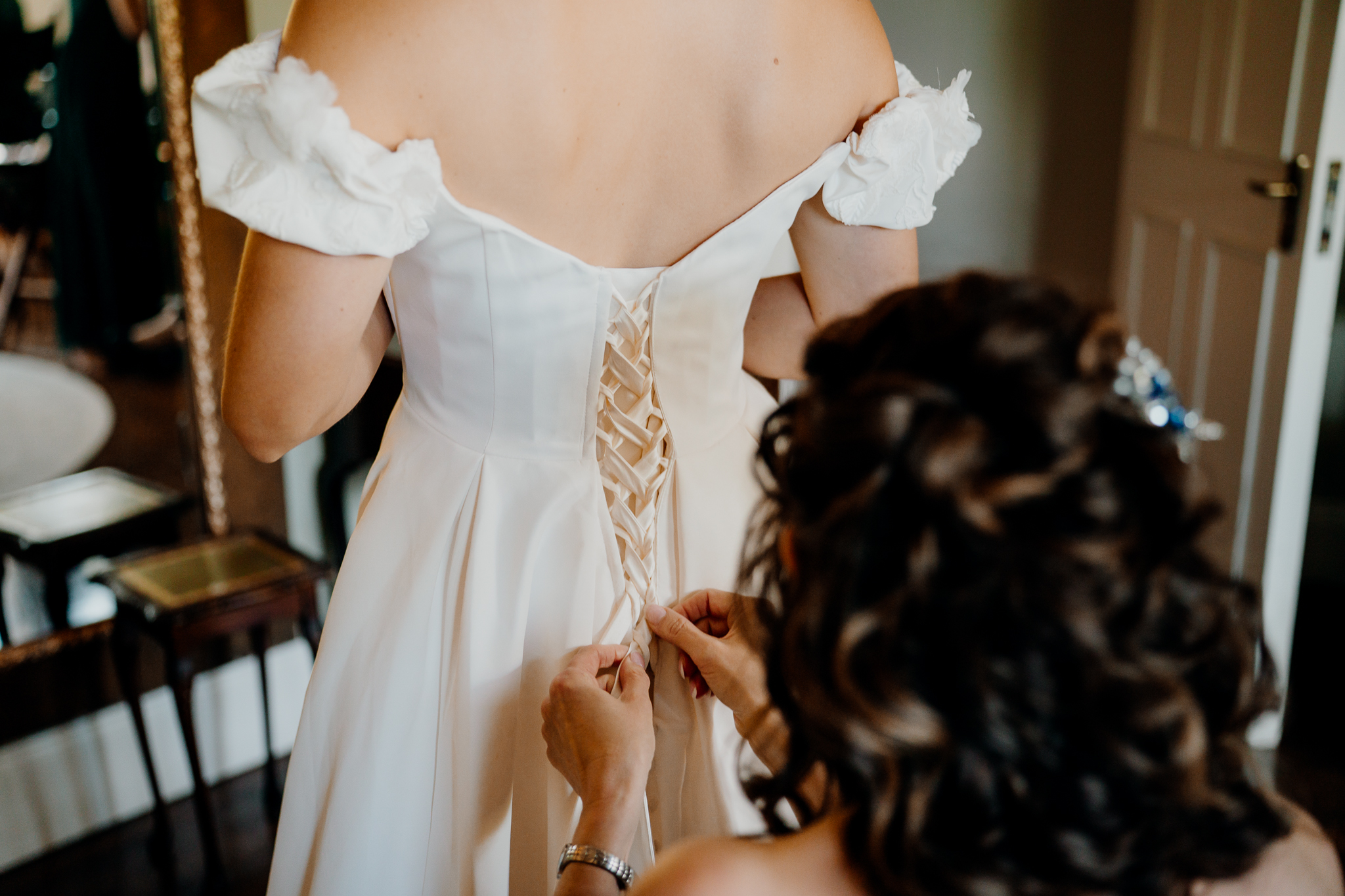 Close-up of a mother fastening the buttons on her daughter's wedding dress in the Bridal Suite at Markree Castle.