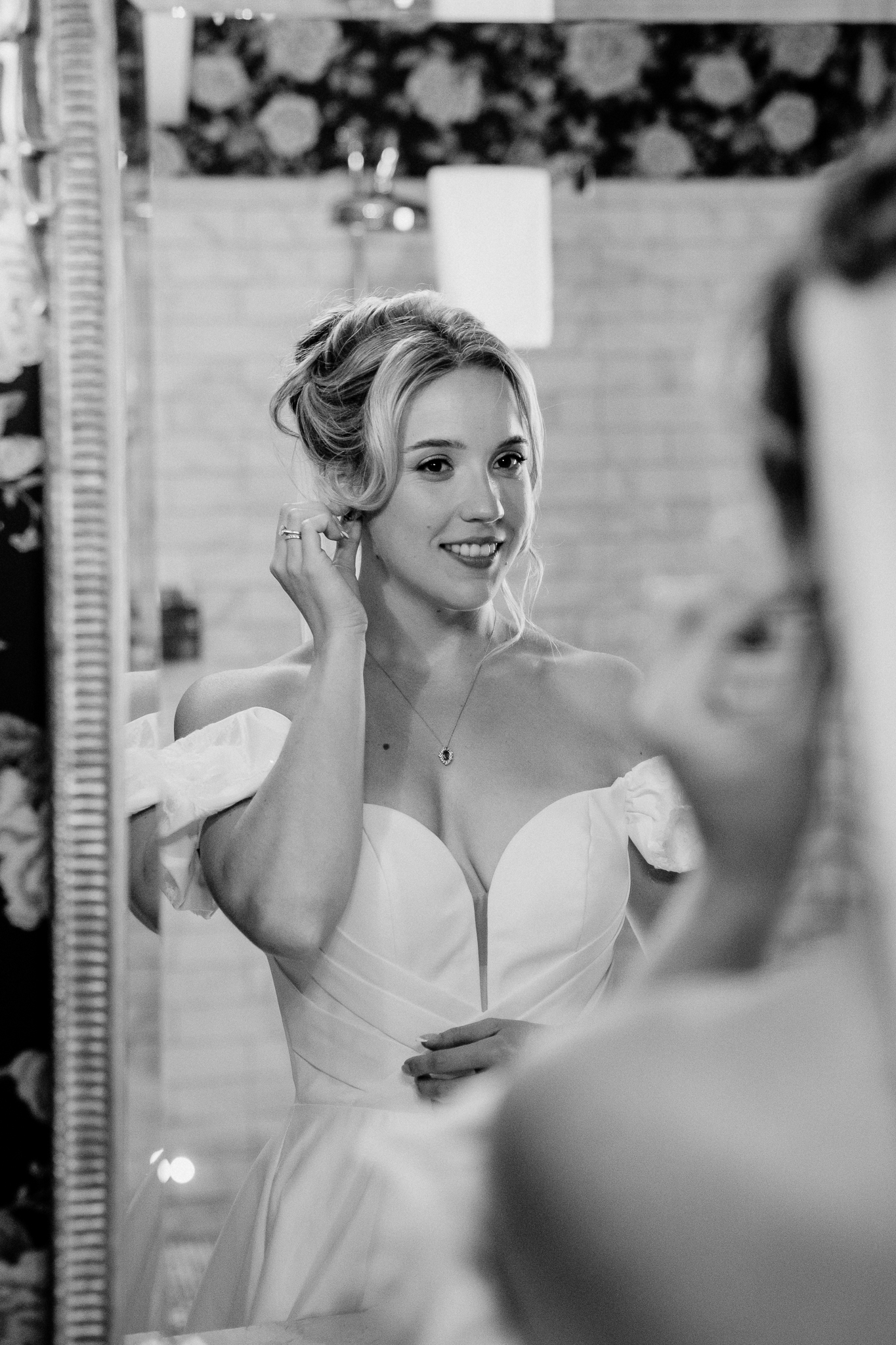 Black and white portrait of a bride adjusting her earrings beside a mirror in the Bridal Suite at Markree Castle.