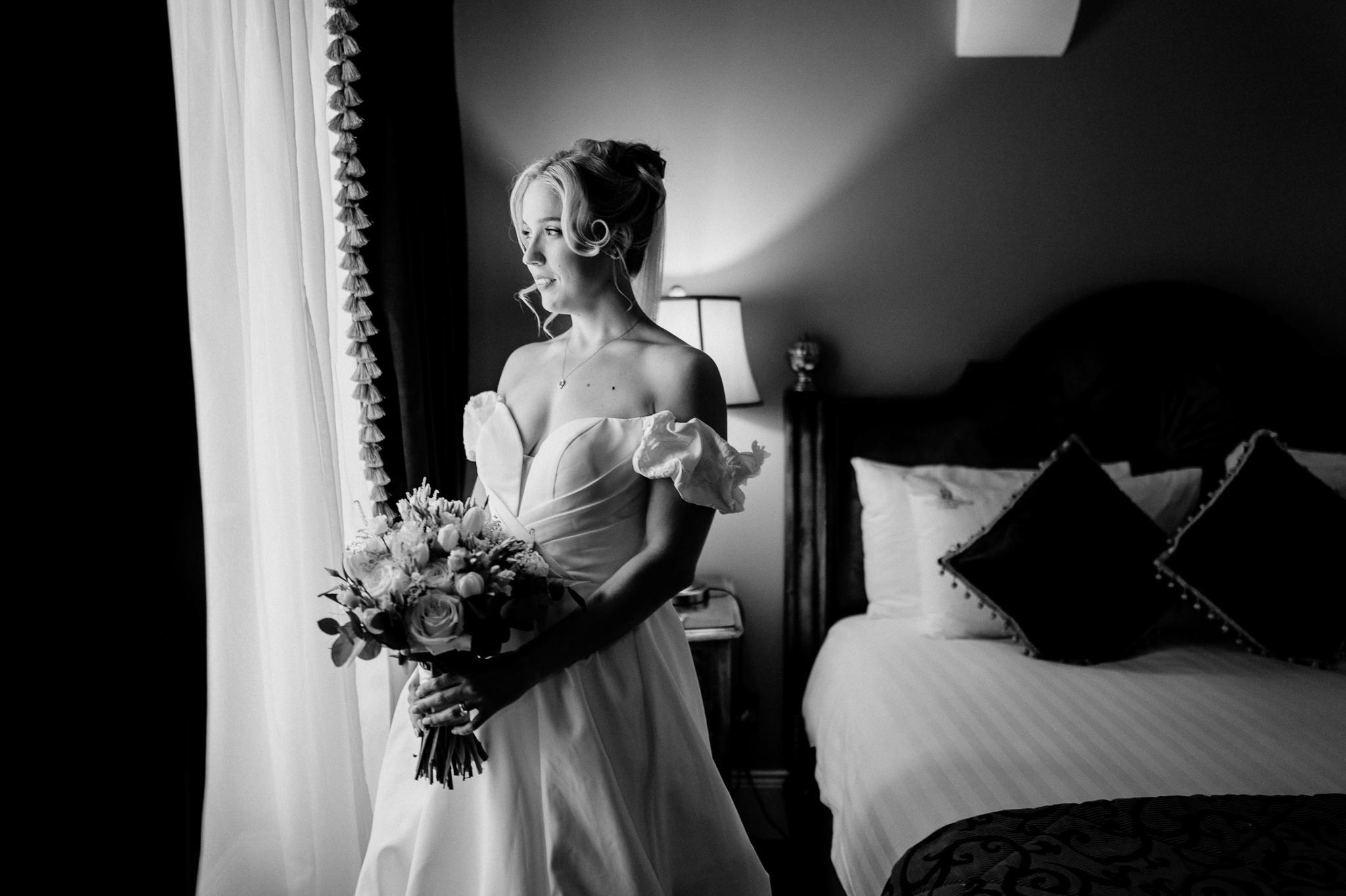 Black and white portrait of a bride in her wedding dress beside a window in the Bridal Suite at Markree Castle.