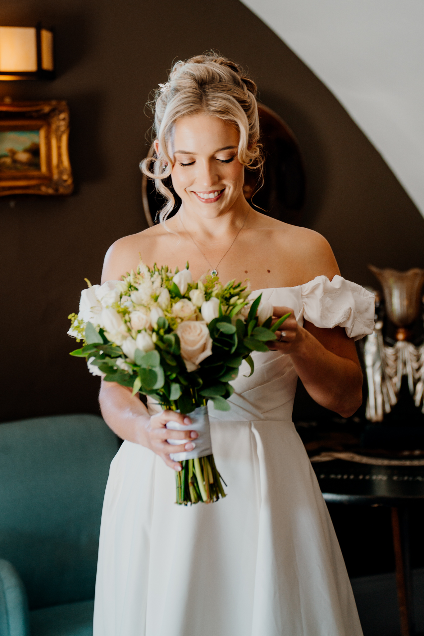 Smiling bride in an off-the-shoulder wedding dress photographed in the Butler's Kitchen at Markree Castle.