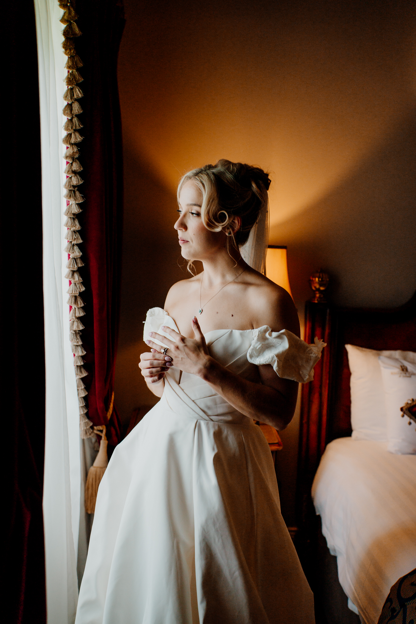Bride in her wedding dress standing beside a window during bridal preparations at Markree Castle.
