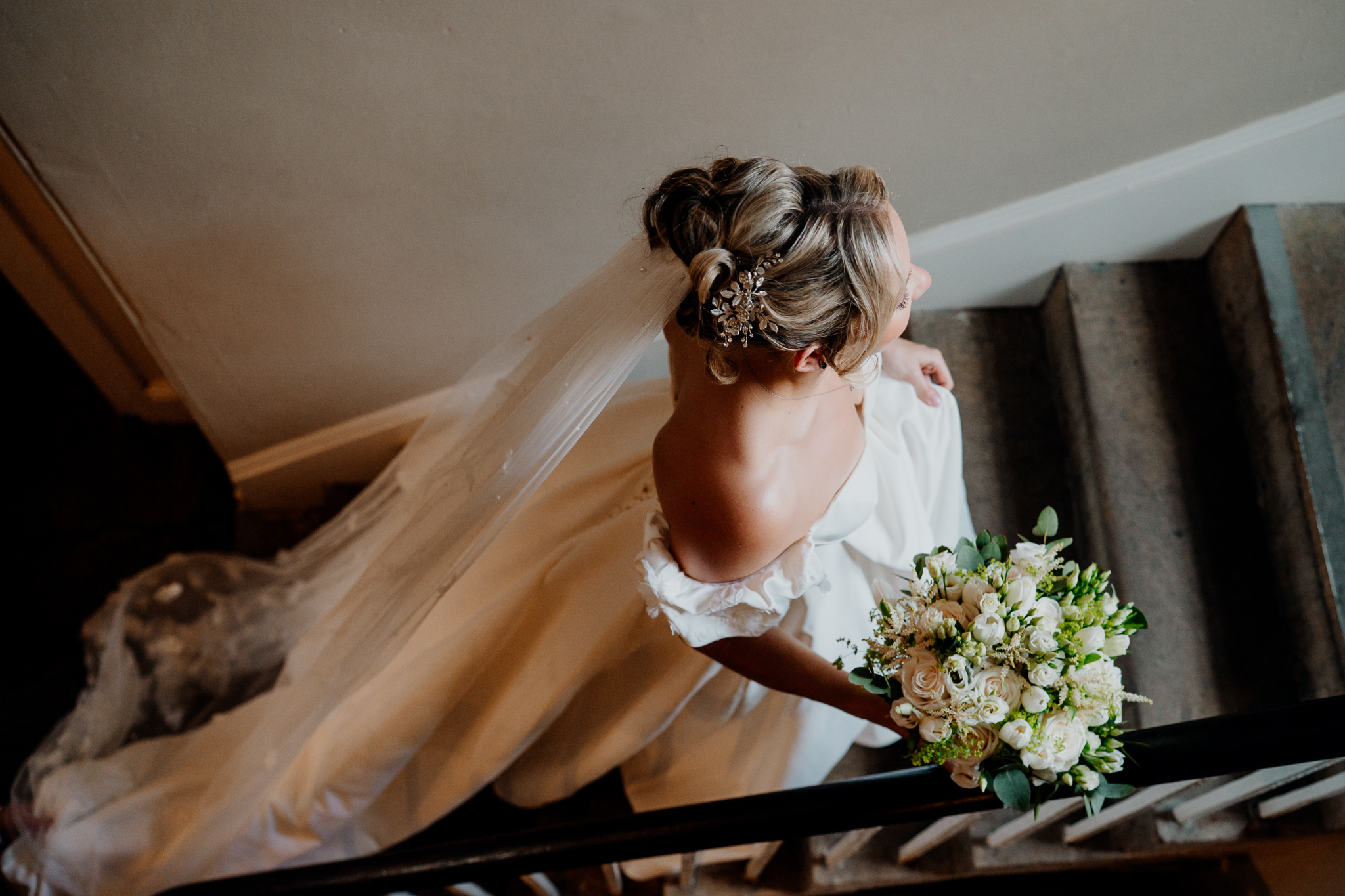 Black and white photograph of a bride walking down the staircase at Markree Castle on her way to the wedding ceremony.
