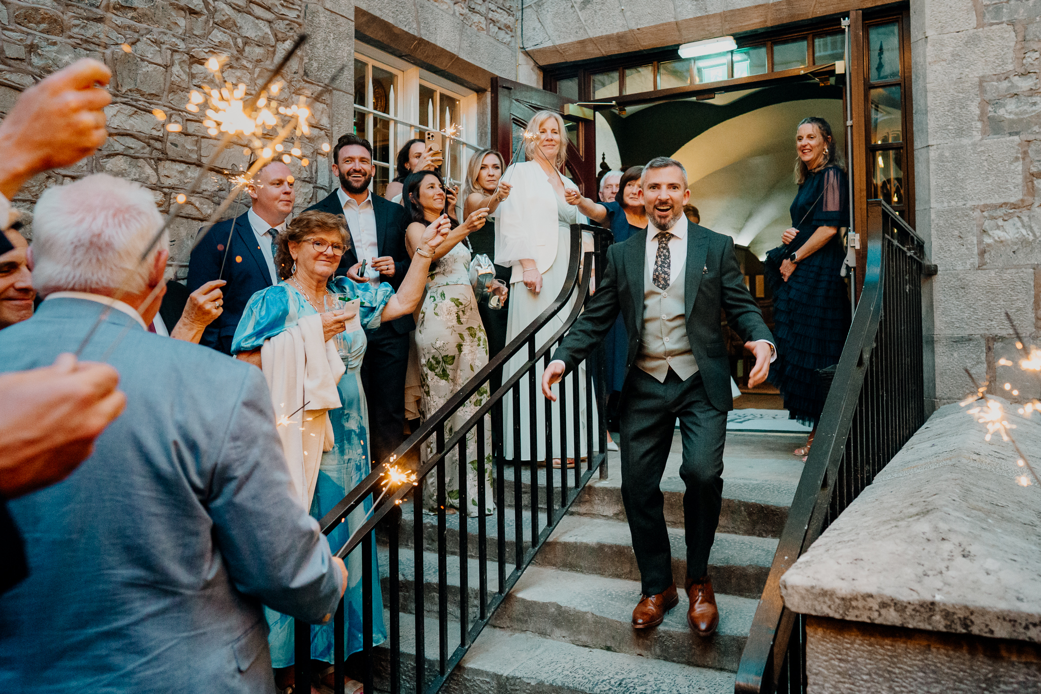Bride Zoe and groom Mark celebrating with wedding guests on the stone steps of the courtyard at Markree Castle, County Sligo.