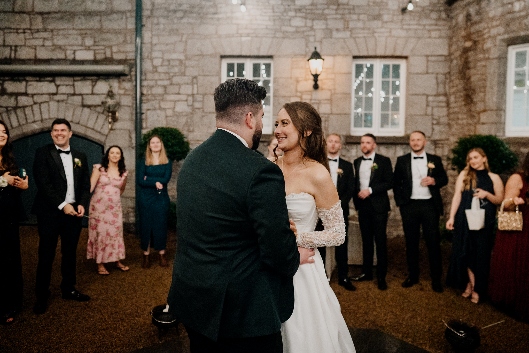 Bride and groom dancing together outdoors in the courtyard at Markree Castle, with wedding guests watching nearby.