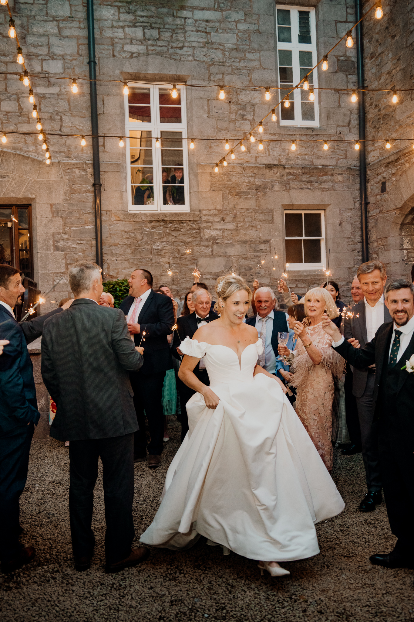Bride Zoe and groom Mark celebrating with wedding guests on the stone steps of the courtyard at Markree Castle, County Sligo.