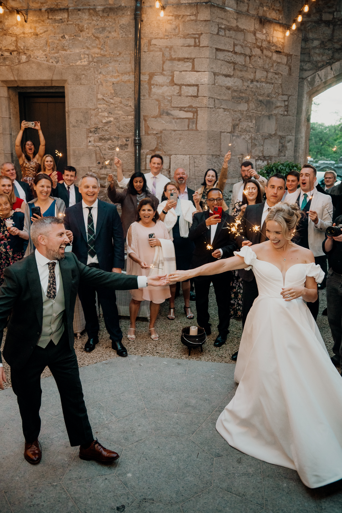 Wedding guests watching and smiling beneath string lights during an outdoor first dance in the courtyard at Markree Castle.