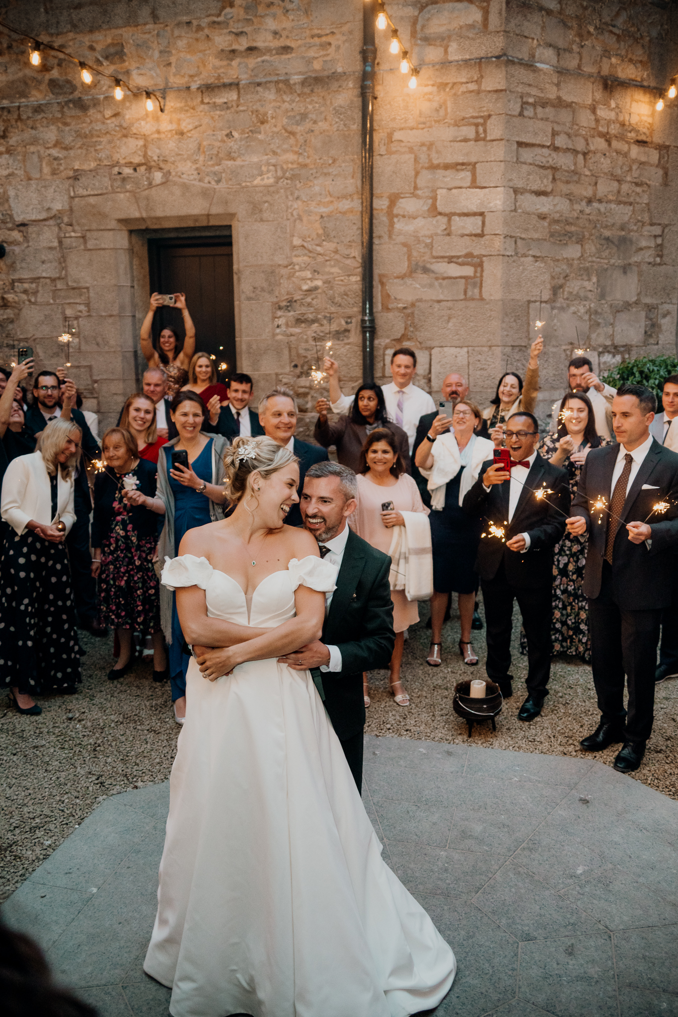 Bride Zoe and groom Mark dancing together in the Markree Castle courtyard, surrounded by wedding guests and historic stone walls.