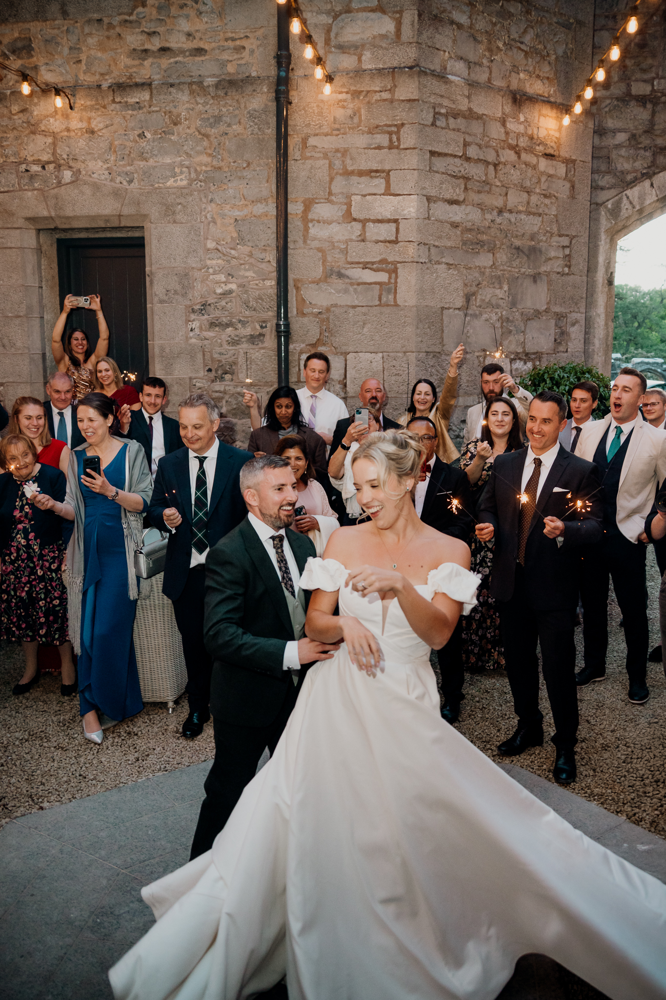 Bride and groom sharing their first dance outdoors in the courtyard at Markree Castle with wedding guests watching.