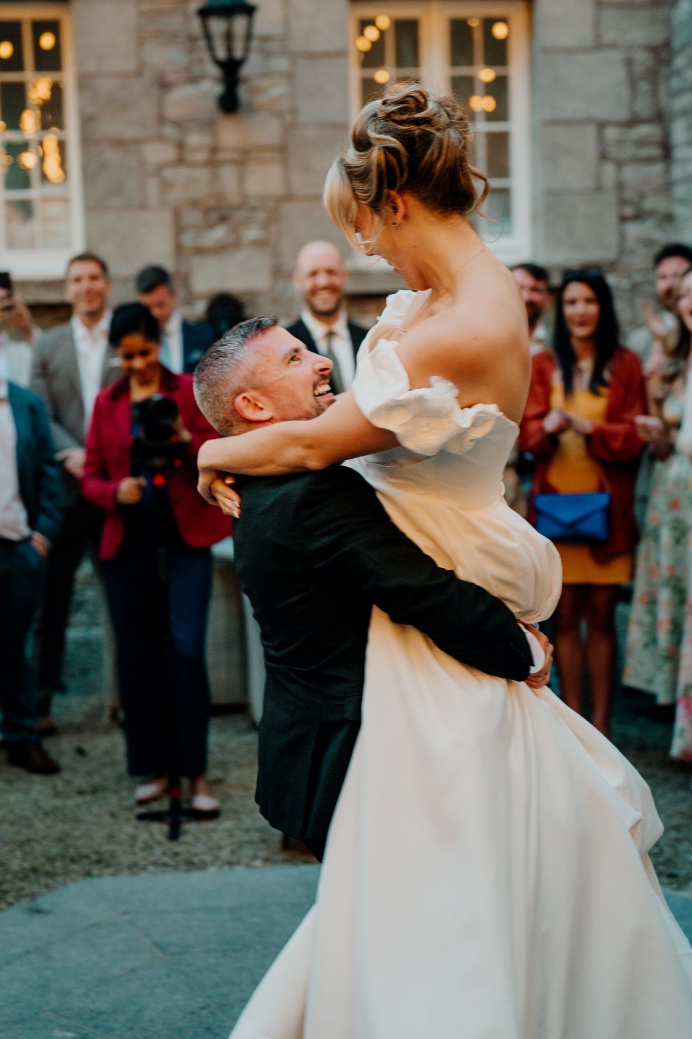 Bride Zoe smiling at groom Mark during their first dance in the courtyard at Markree Castle, surrounded by guests.