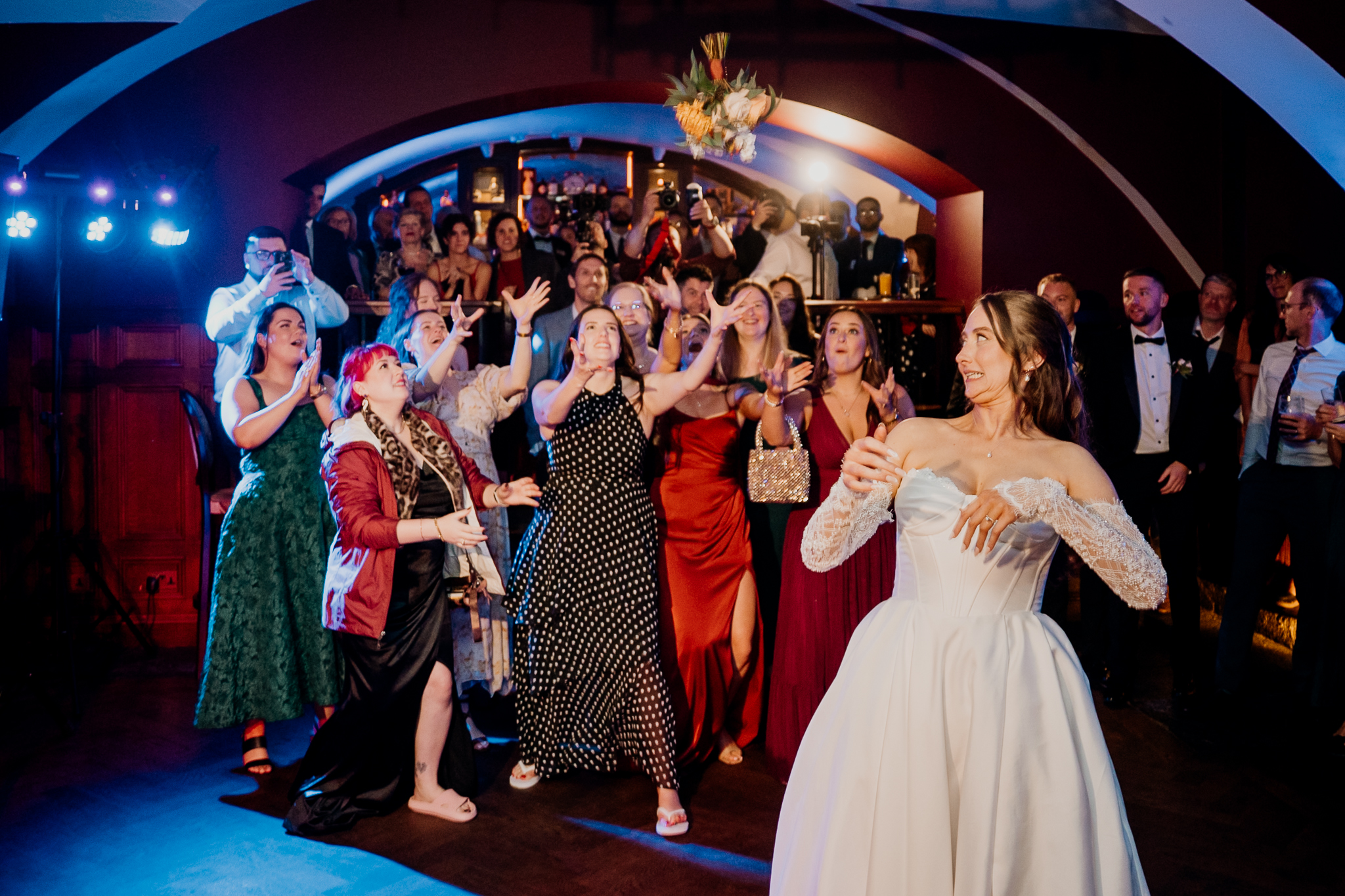 Groom throwing a bouquet towards cheering wedding guests during the evening party at Markree Castle.