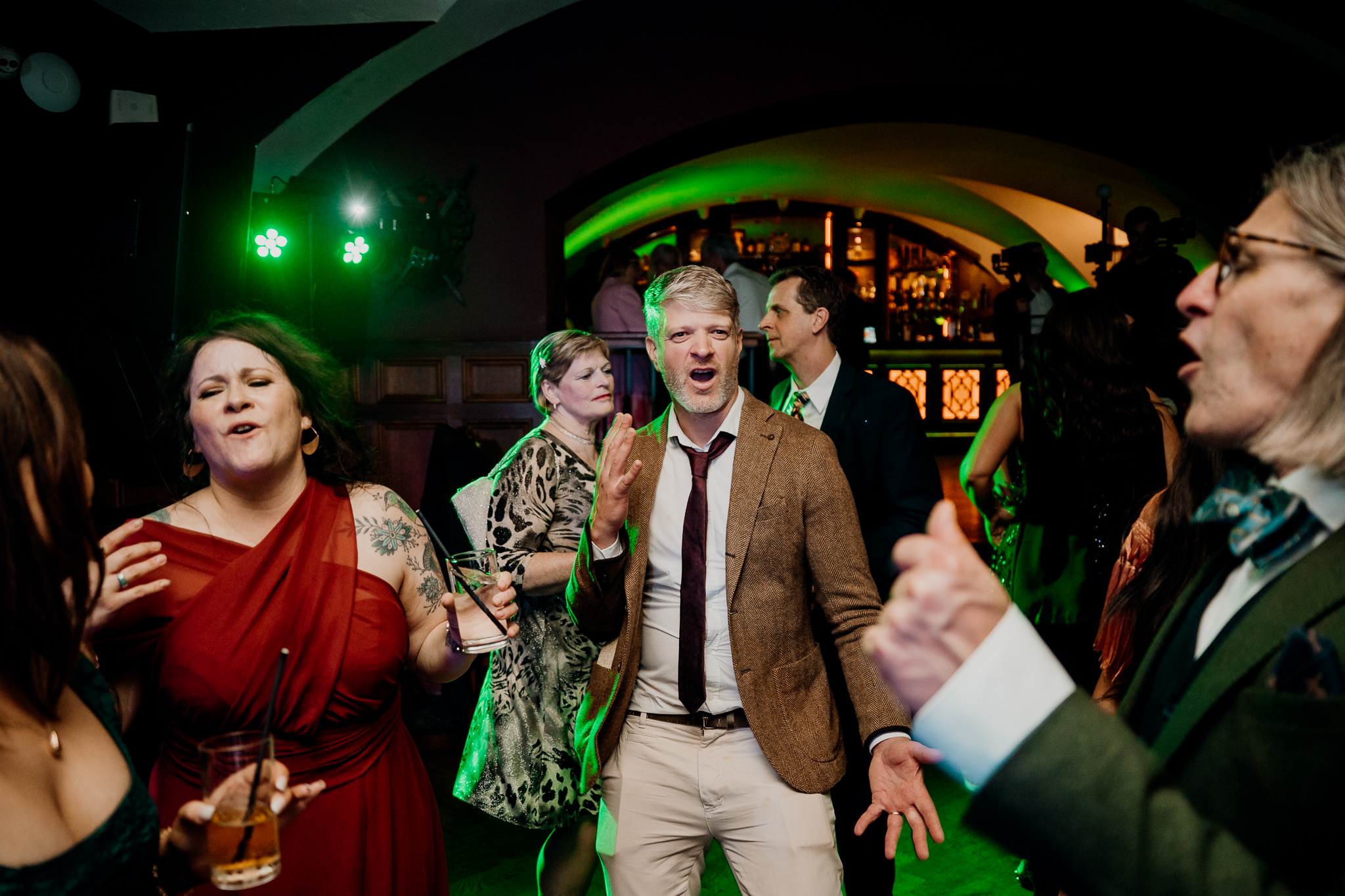 Male wedding guest singing along and celebrating beneath green party lights on the dance floor at Markree Castle.