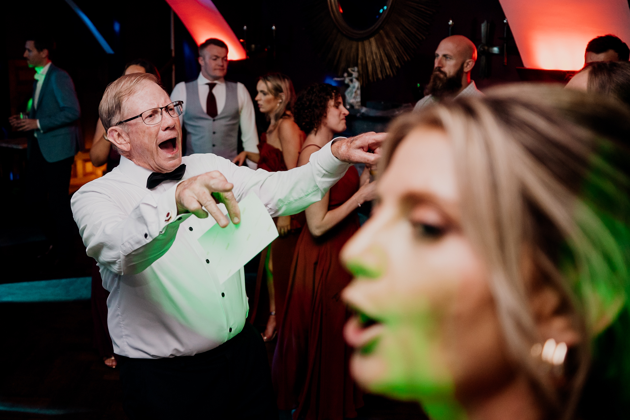 Wedding guests cheering and dancing together under colourful party lights at Markree Castle.