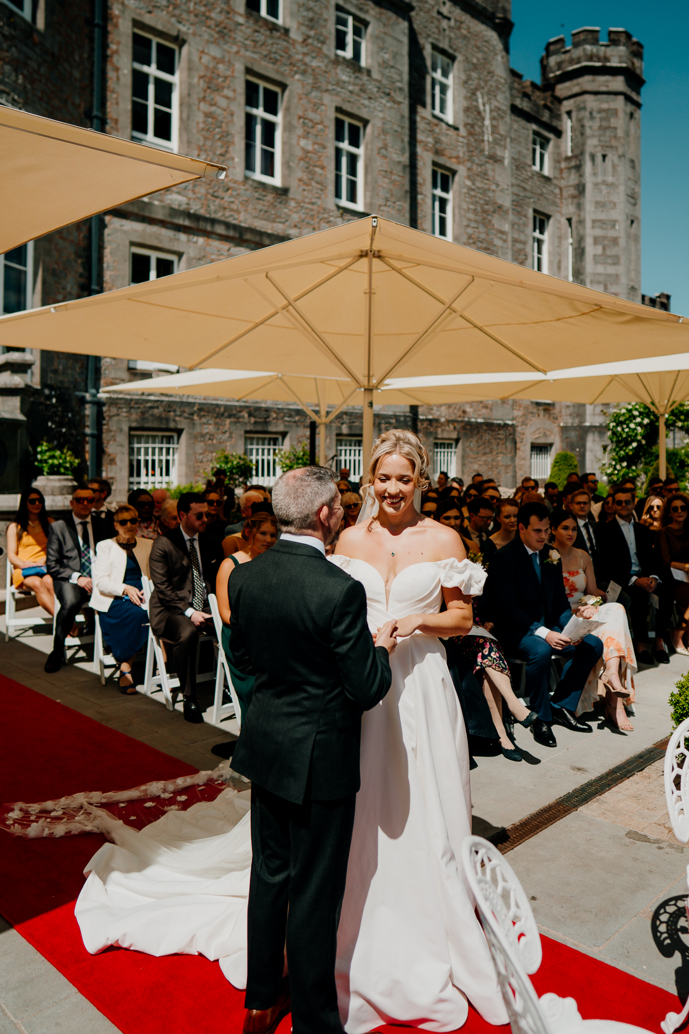 Outdoor garden wedding ceremony beneath cream parasols on the terrace at Markree Castle, County Sligo.