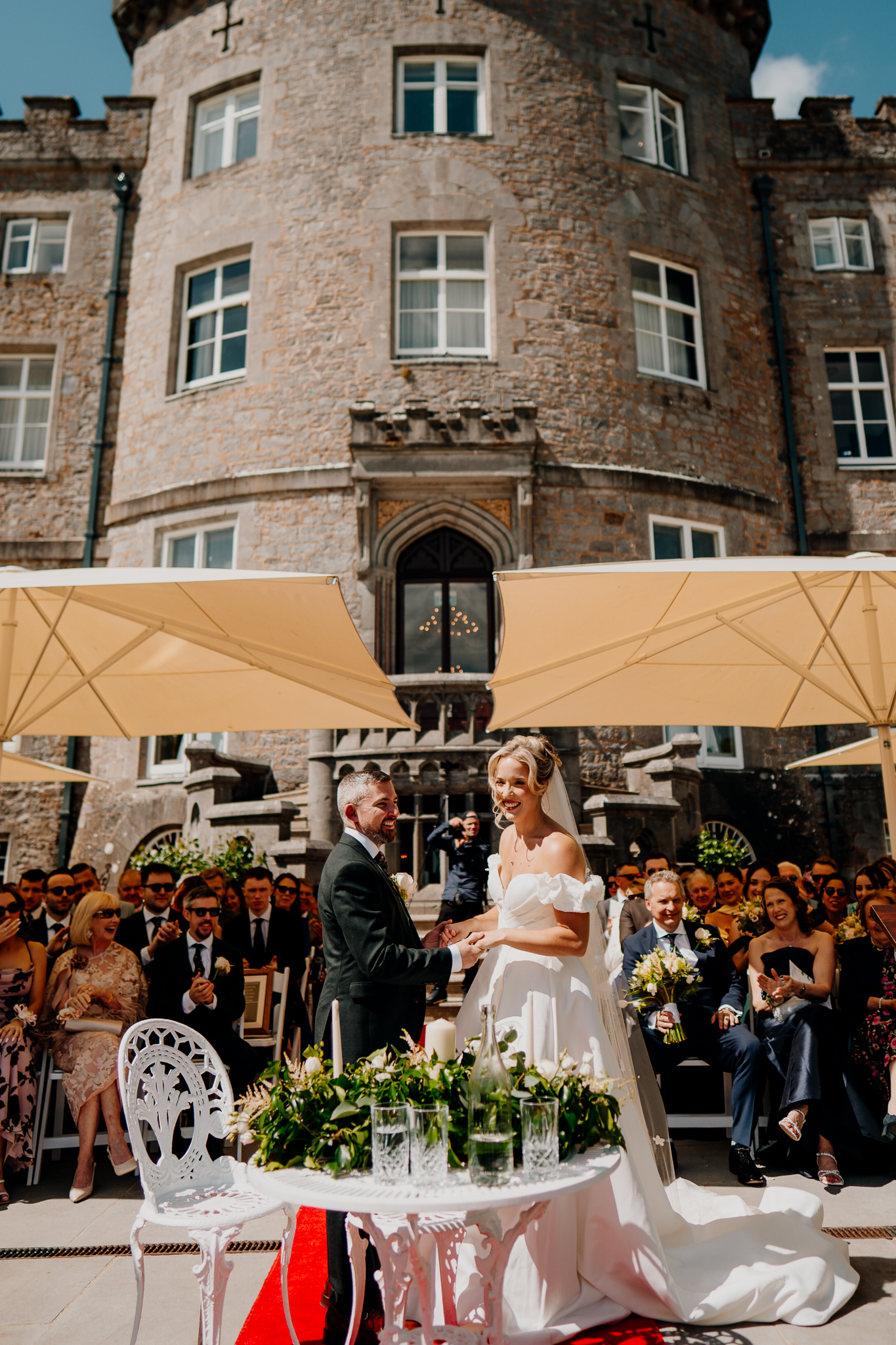 Outdoor wedding ceremony terrace with cream parasols beside the historic stone facade of Markree Castle.