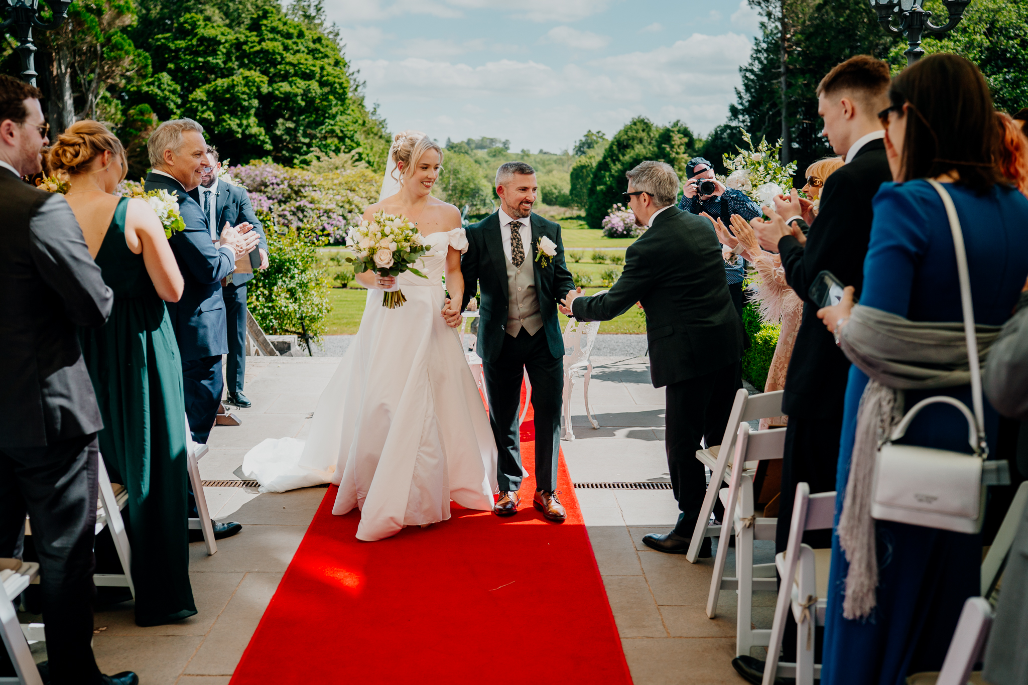 Newly married bride and groom walking back down the aisle after their outdoor garden wedding ceremony at Markree Castle.