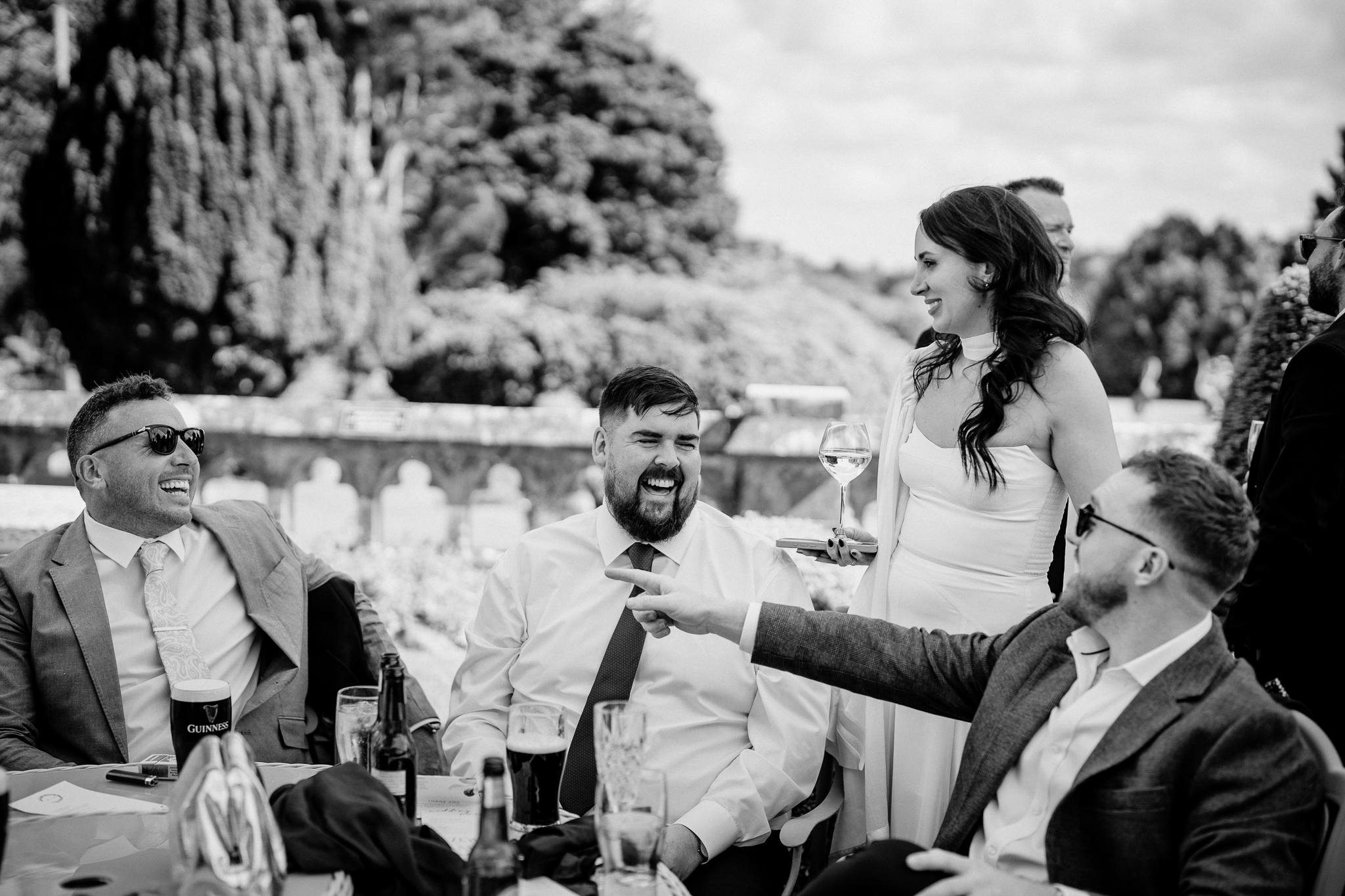 Black and white candid photograph of wedding guests chatting in the gardens of Markree Castle, County Sligo.