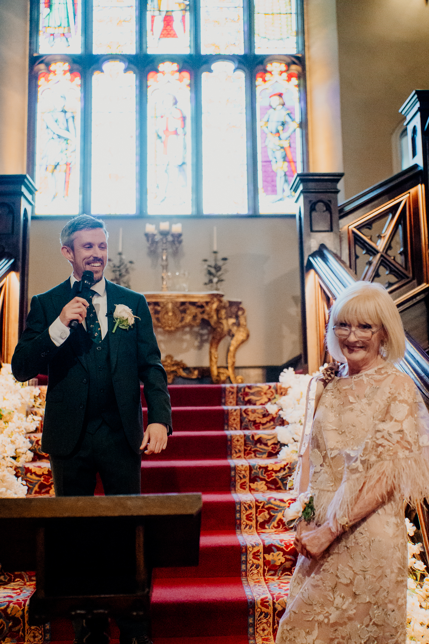 Wedding speech beside the grand staircase at Markree Castle, with a man holding a microphone and guests listening.