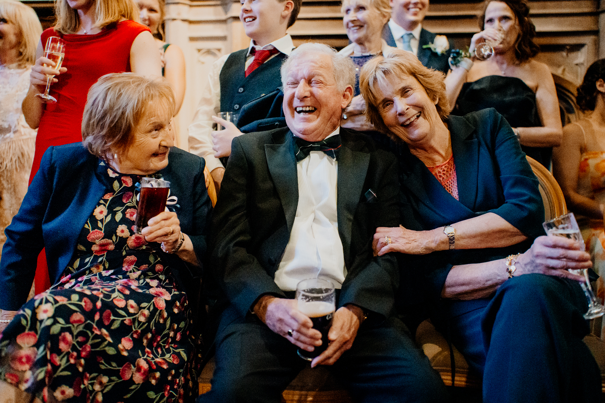 Wedding guests laughing together during speeches inside Markree Castle, including an older gentleman in a black bow tie.
