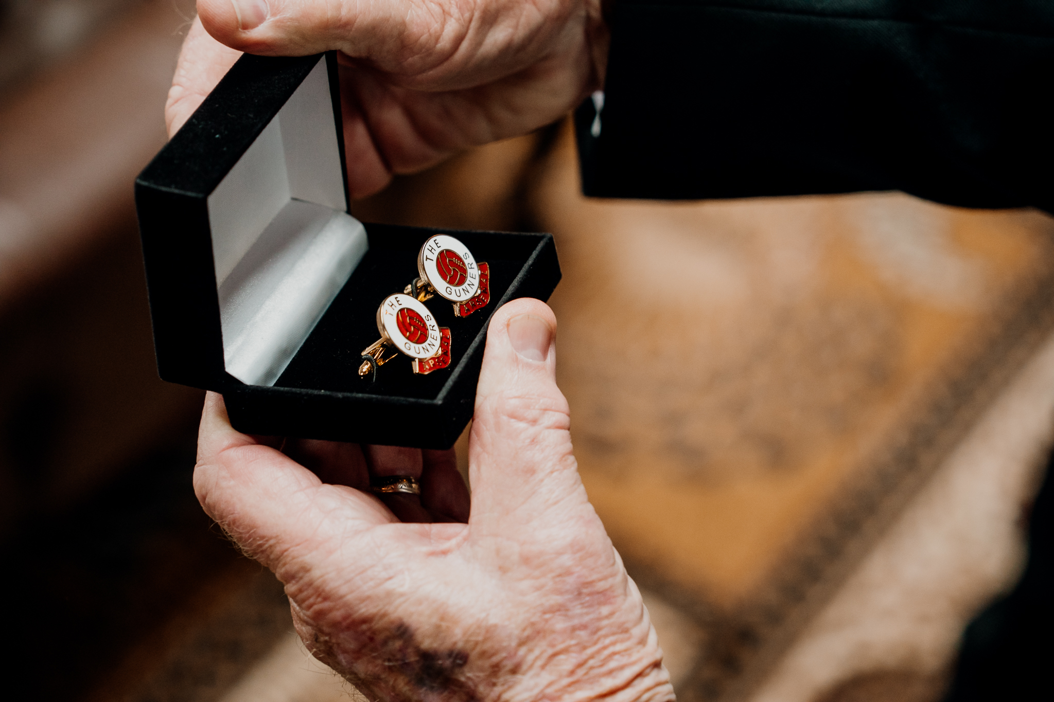 Close-up of the groom fastening red and silver cufflinks to his white shirt during wedding preparations at Markree Castle.