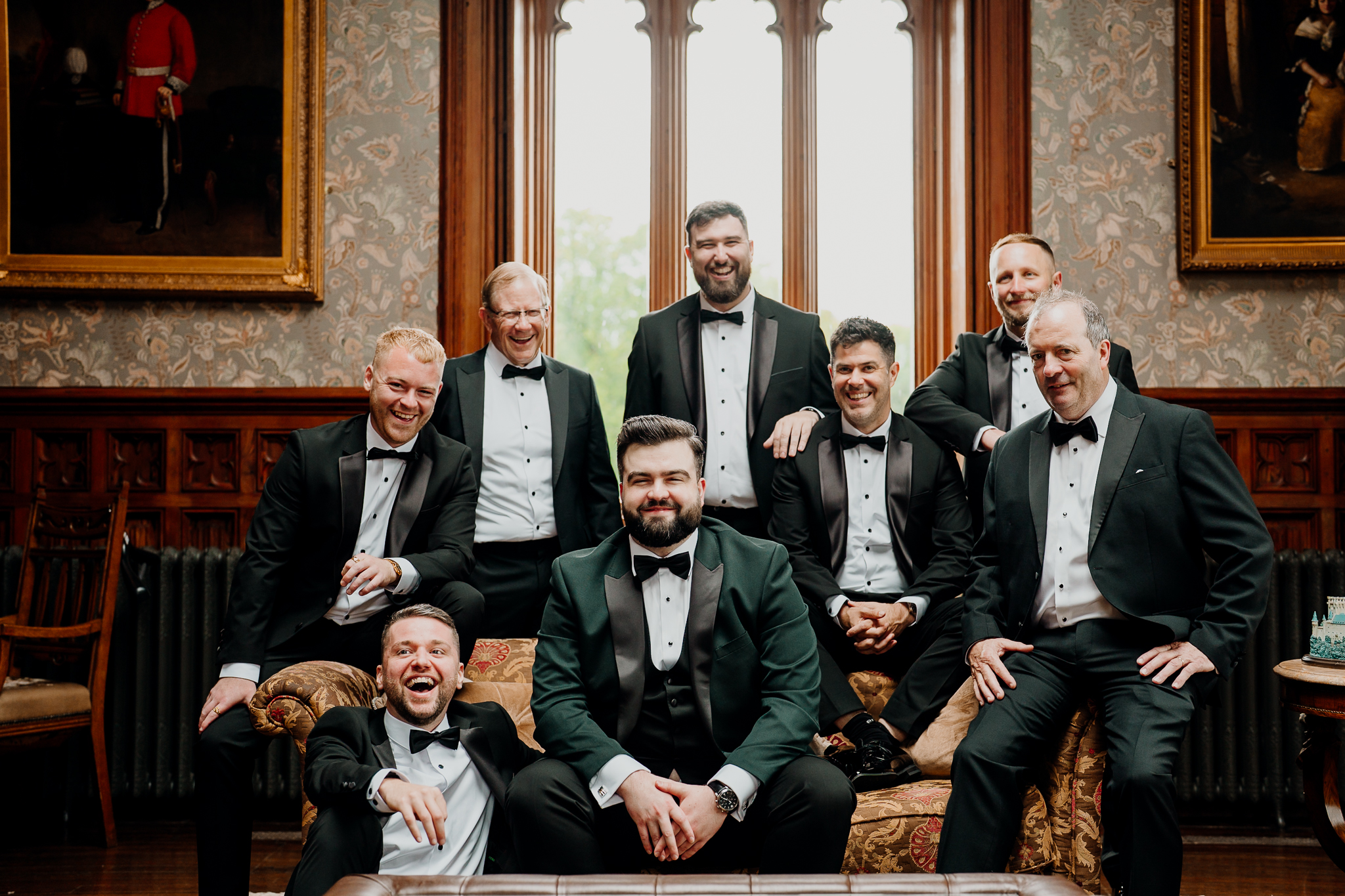 Groom and five groomsmen posing together in front of tall windows inside Markree Castle's Billiard Room.