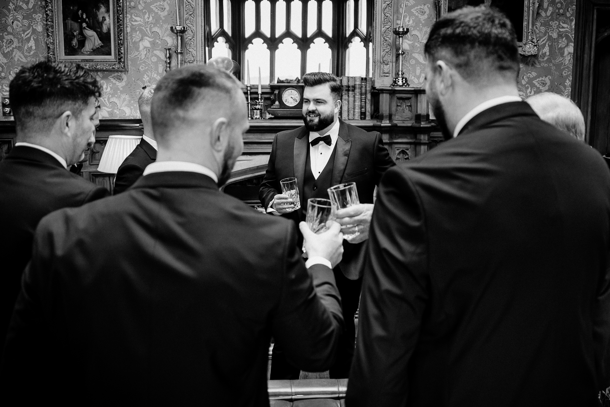 Black and white candid photograph of the groom and groomsmen preparing in the Snooker Room at Markree Castle.