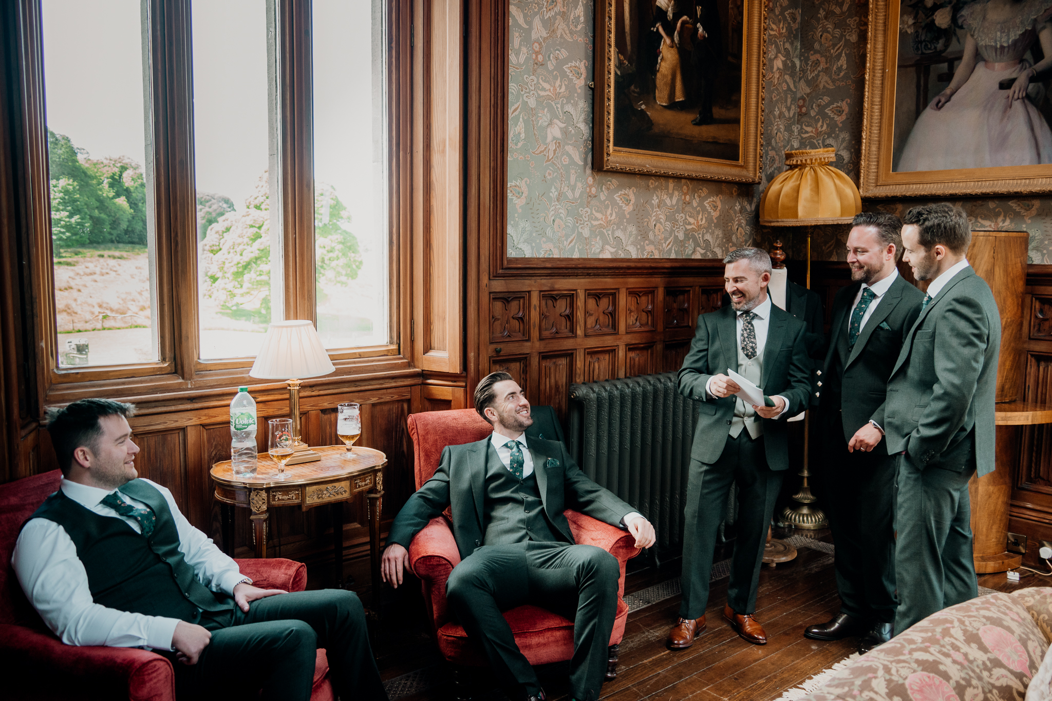 Groom sharing a moment with a groomsman while giving wedding party gifts in the Billiard Room at Markree Castle.