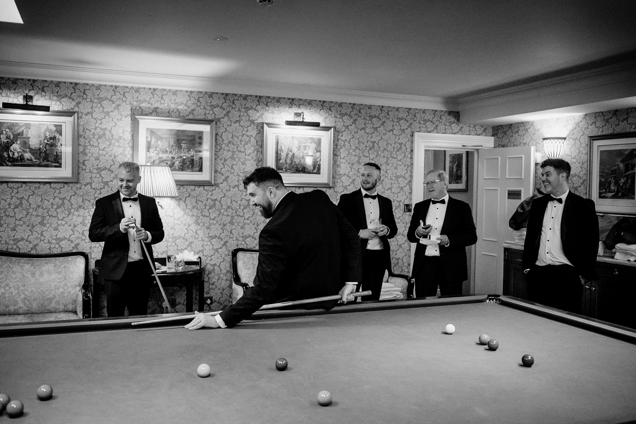Black and white photograph of the groom and groomsmen gathered around a snooker table inside Markree Castle.