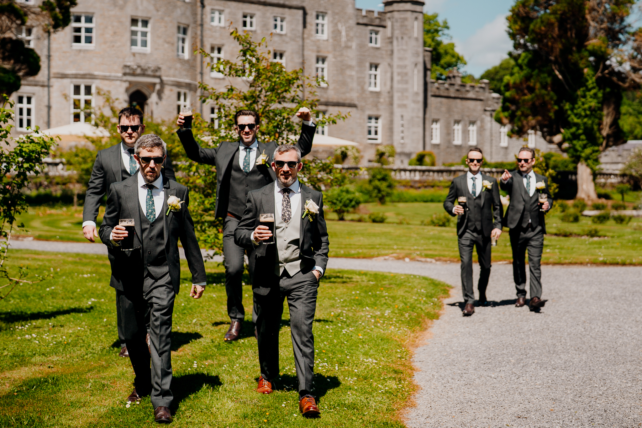 Groom and groomsmen posing outdoors in the gardens with Markree Castle visible behind them.