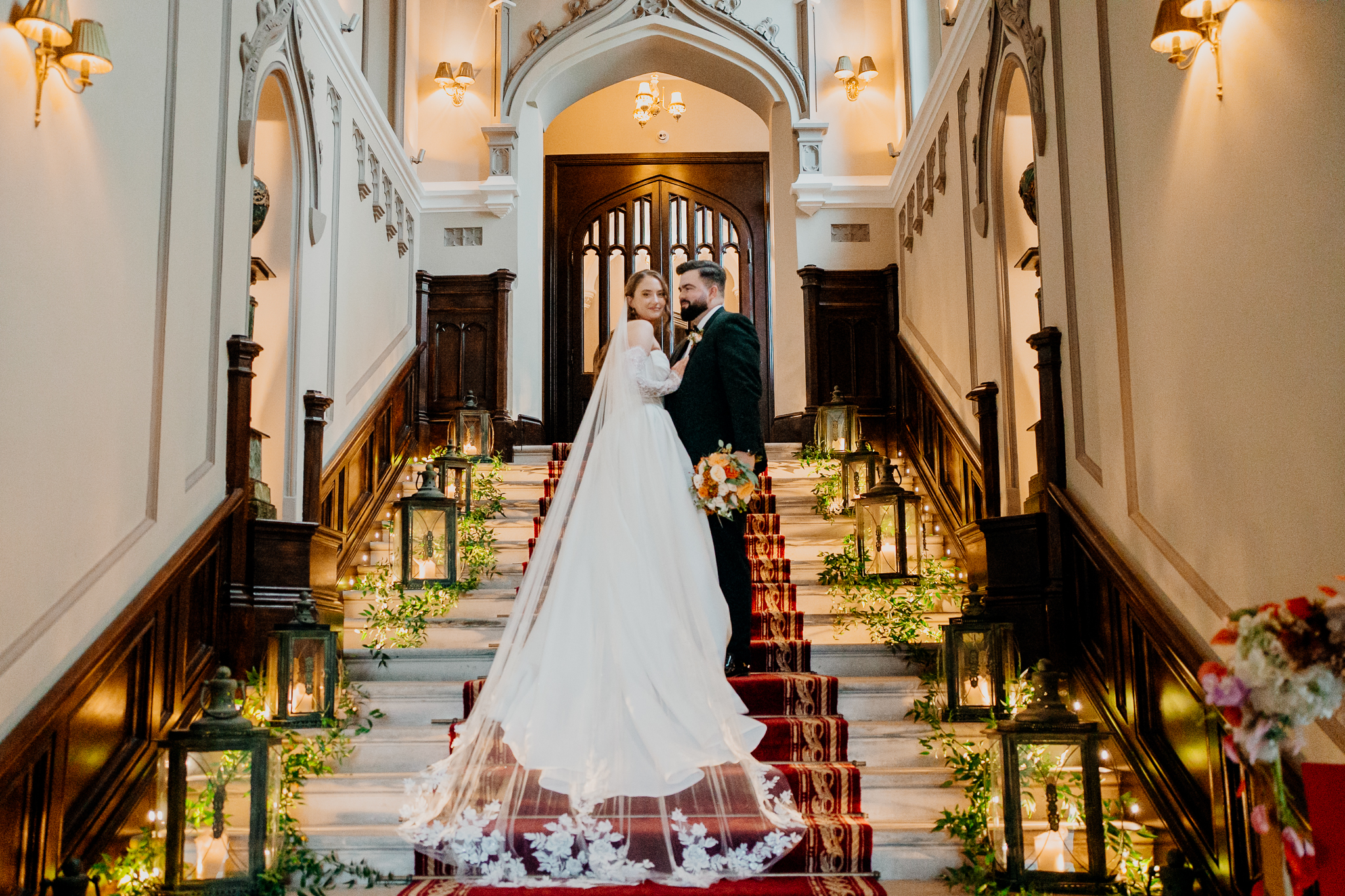 Bride and groom embracing beneath the grand staircase in the historic entrance hall at Markree Castle, Sligo.