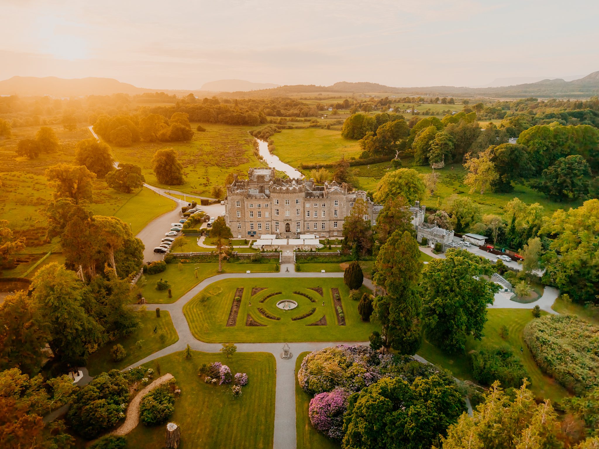 Aerial view of Markree Castle and its formal gardens in County Sligo, Ireland, illuminated by warm golden hour sunlight.