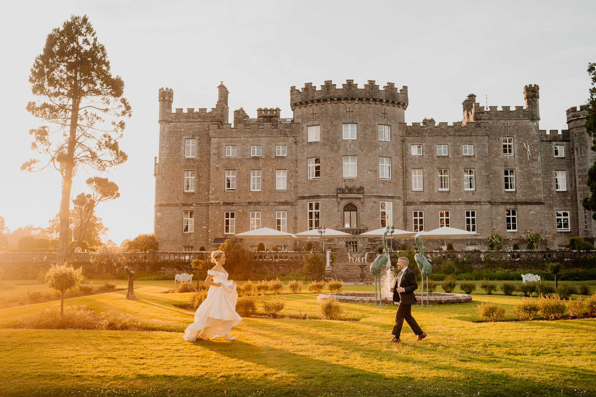 Bride and groom posing on the lawn in front of Markree Castle during their sunset wedding portrait session in County Sligo.
