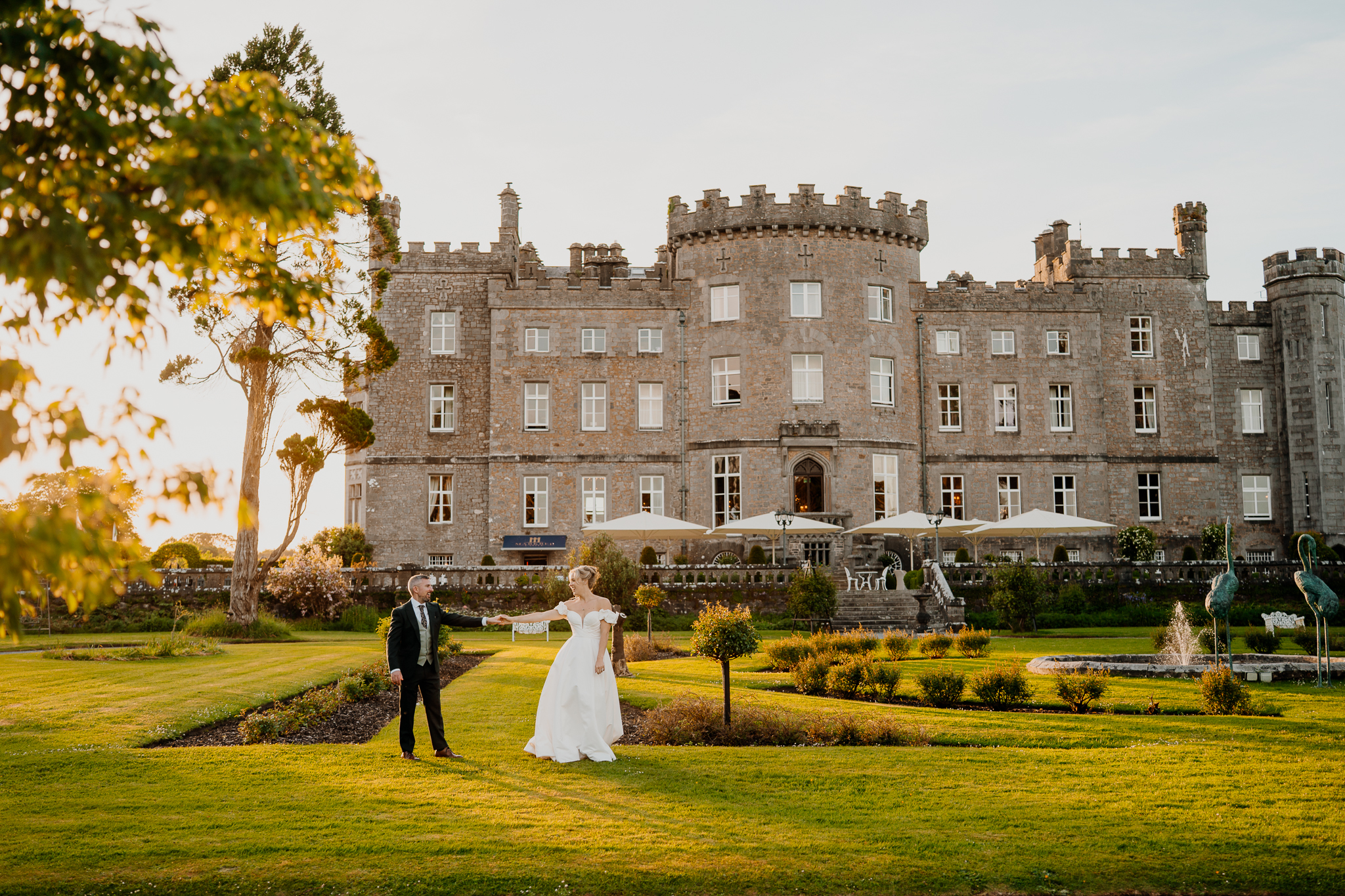 Wide wedding portrait of Zoe and Mark standing together on the lawn with the full historic facade of Markree Castle behind them.