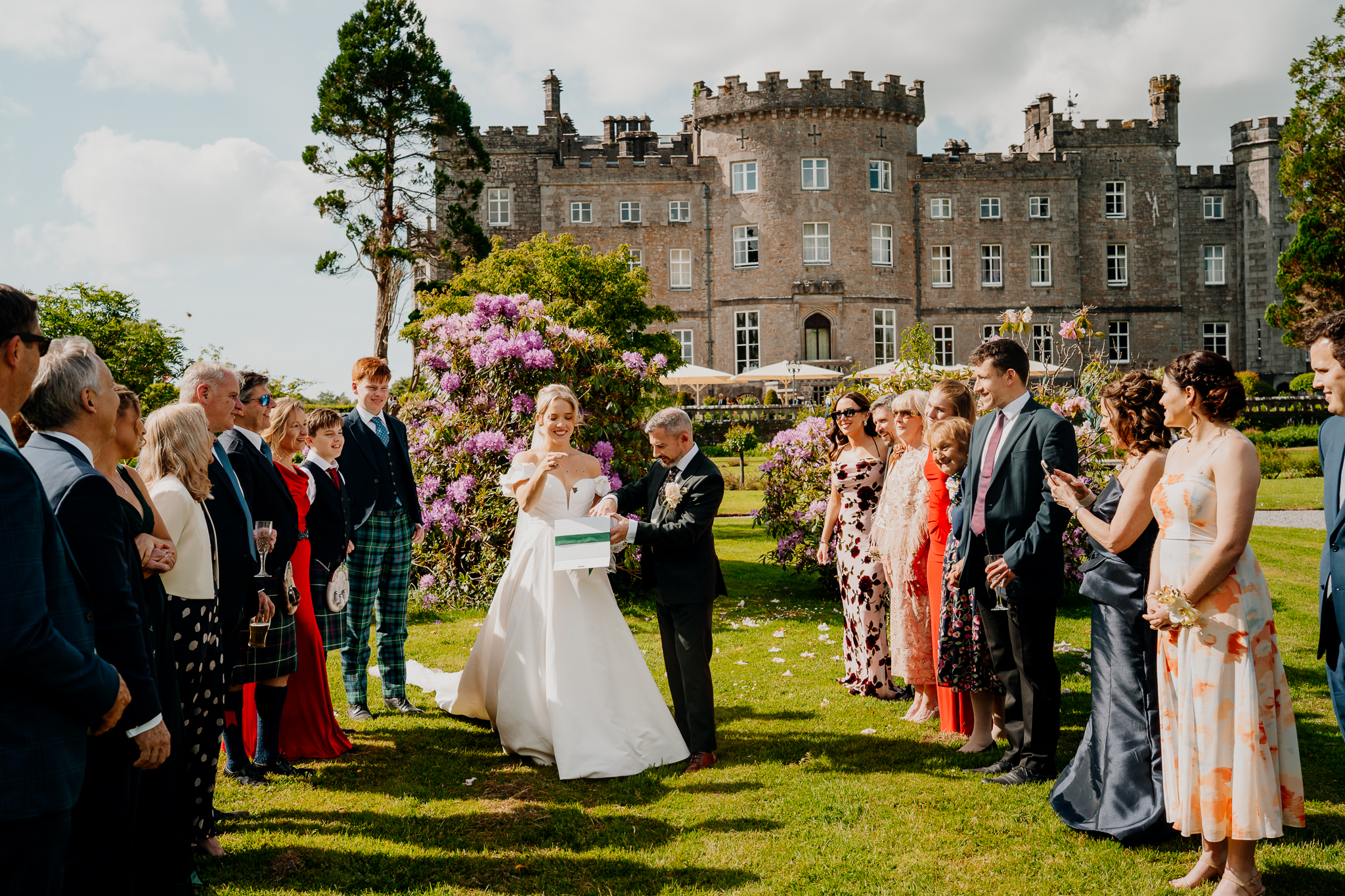 Wedding guests gathered around Zoe and Mark for a butterfly release in the gardens with Markree Castle in the background.