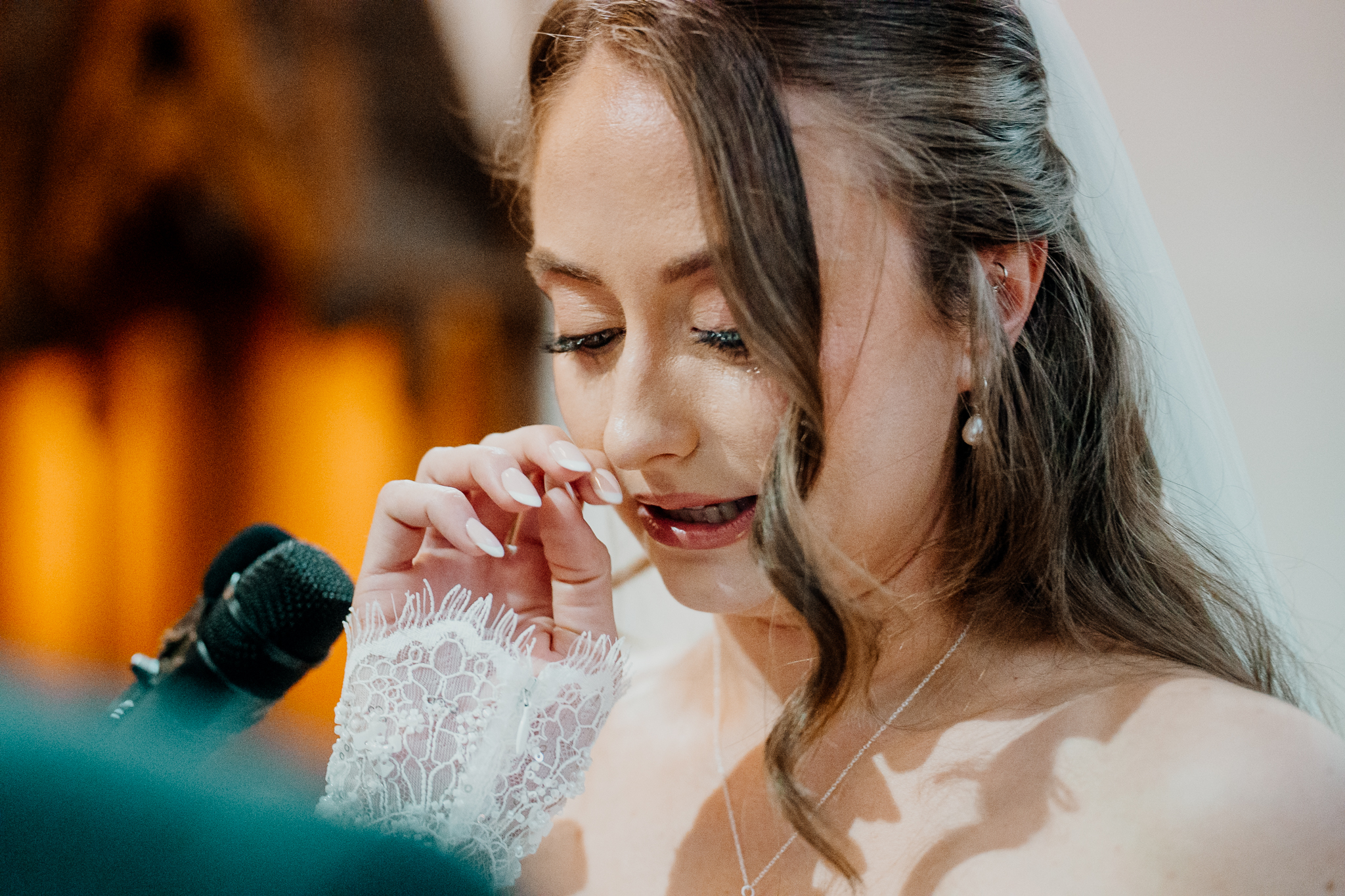 Emotional close-up of bride Amy wiping away tears during her wedding ceremony at Markree Castle Chapel.
