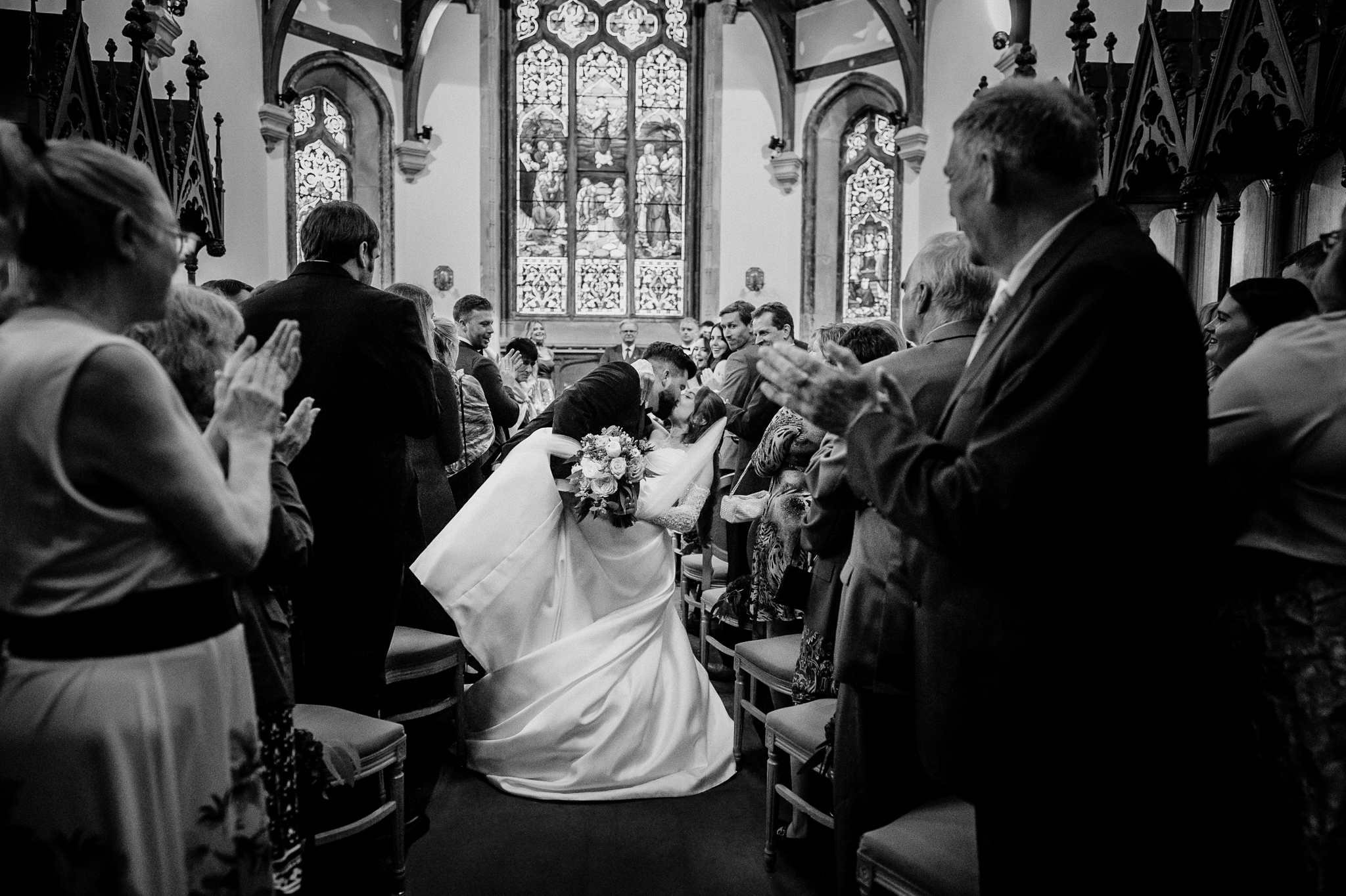 Black and white documentary photograph of newlyweds leaving Markree Castle Chapel through a crowd of wedding guests.